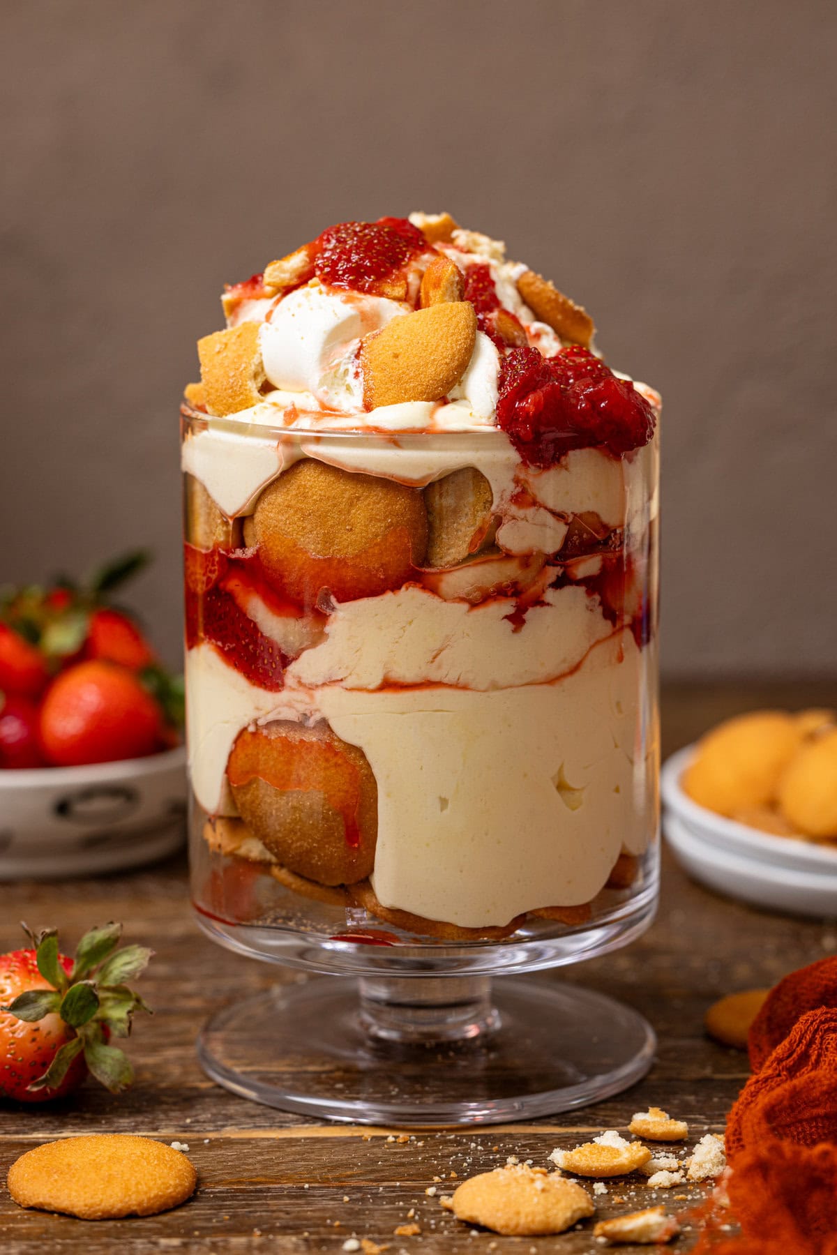 Strawberry banana pudding with strawberries and cookies in the background. 