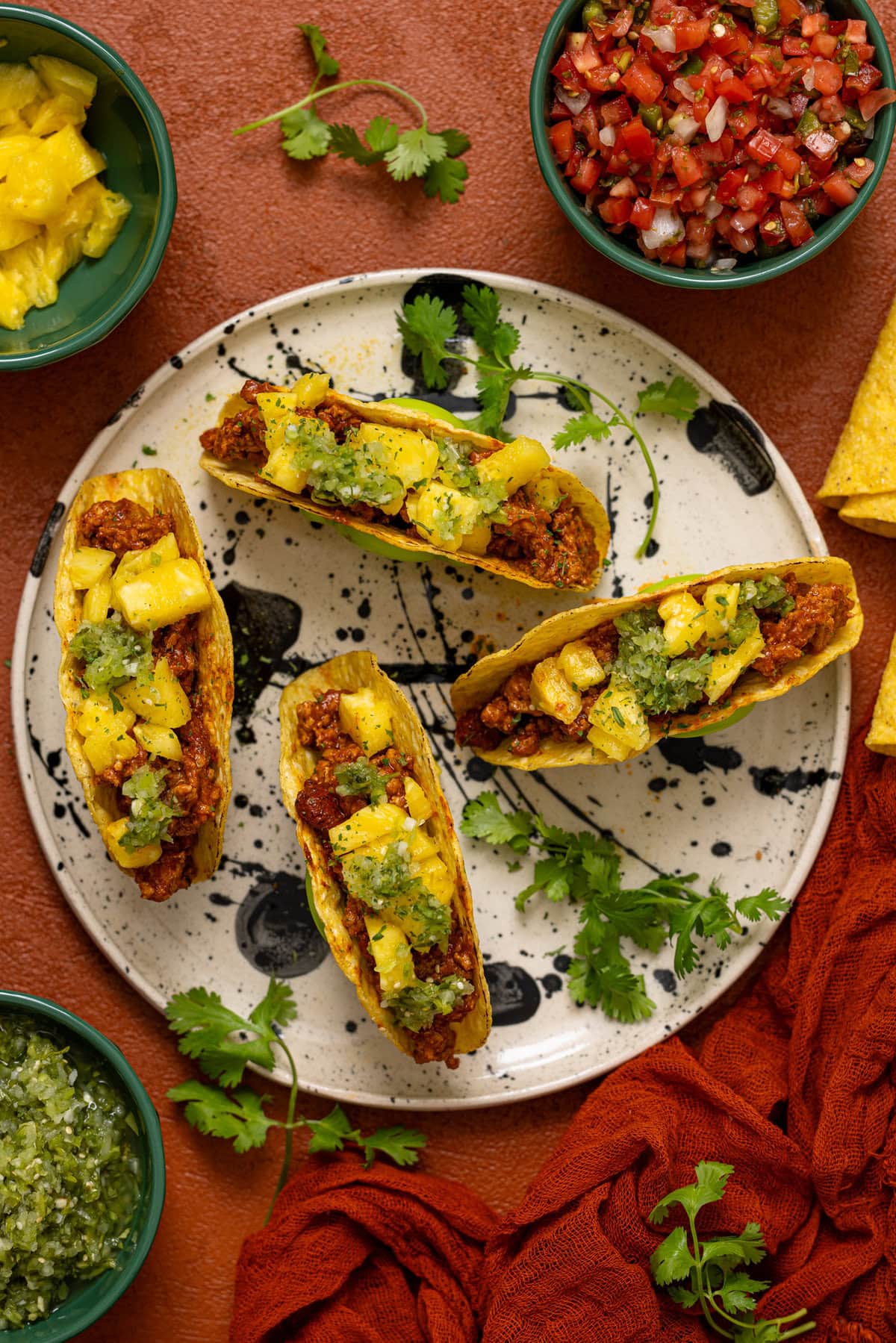 Tacos on a plate with bowls filled with toppings.