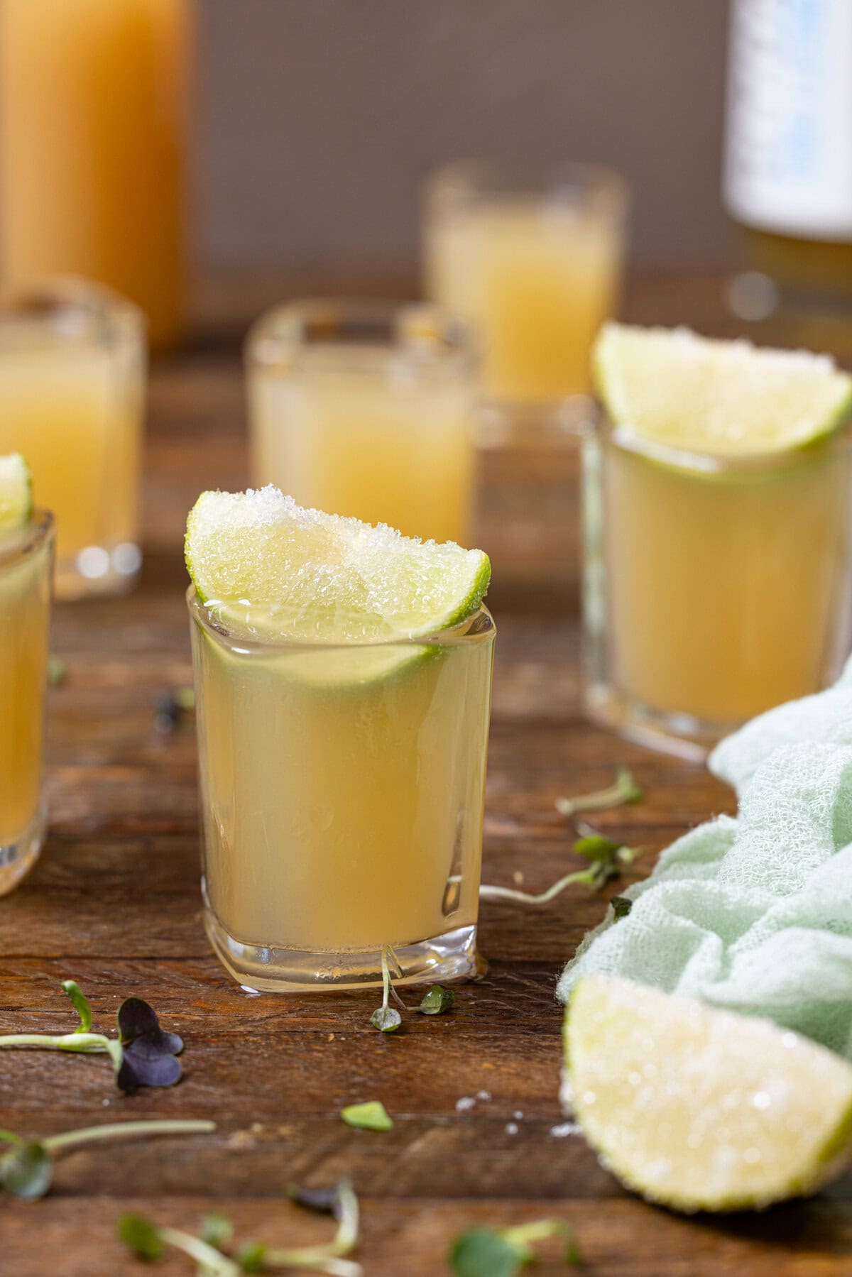 Green tea shots on a brown wood table with lime.