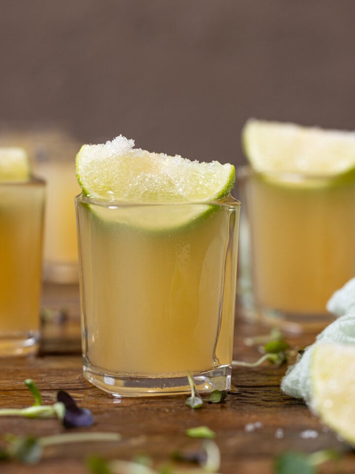 Up close shot of green tea shots with lime wedges.