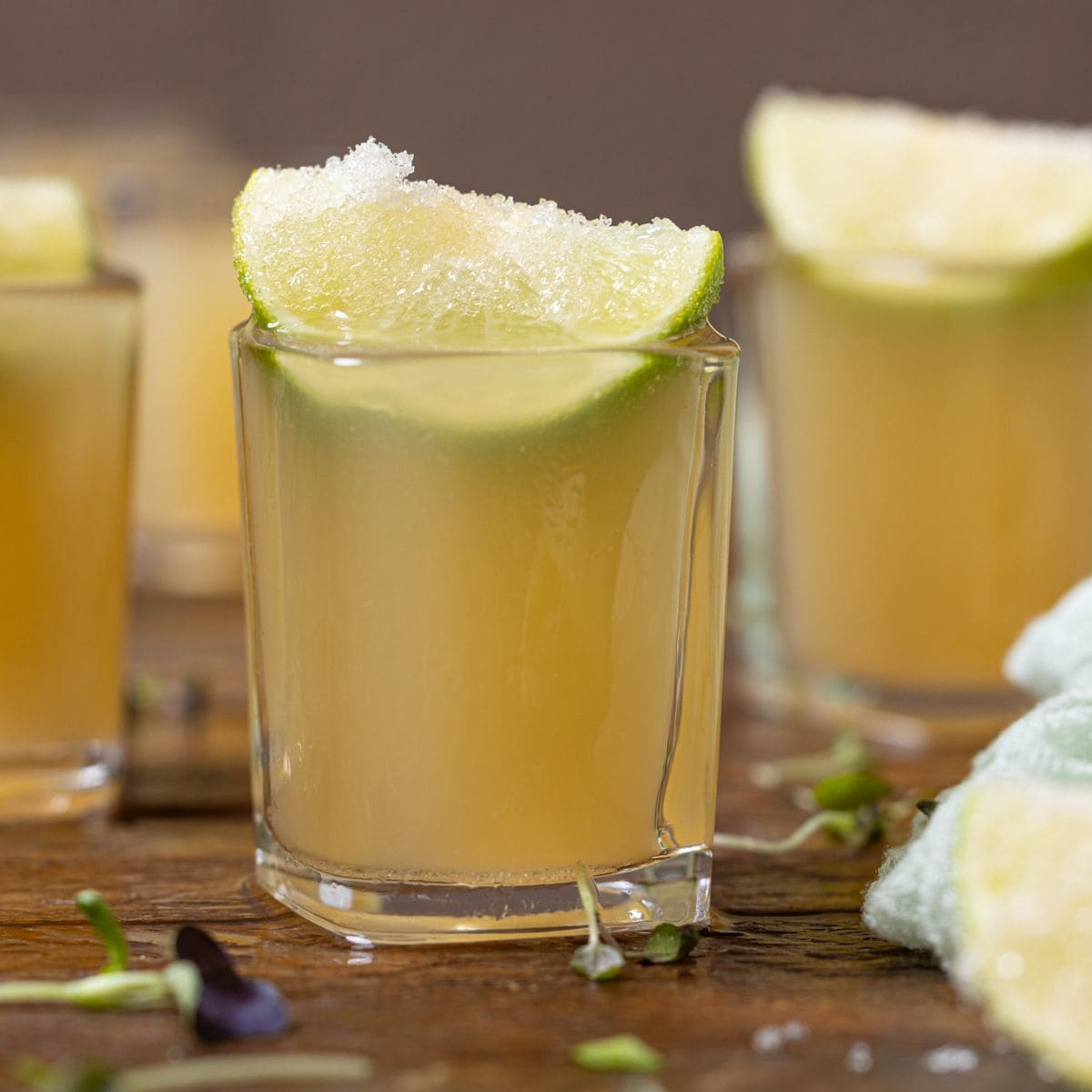 Up close shot of green tea shots with lime wedges.