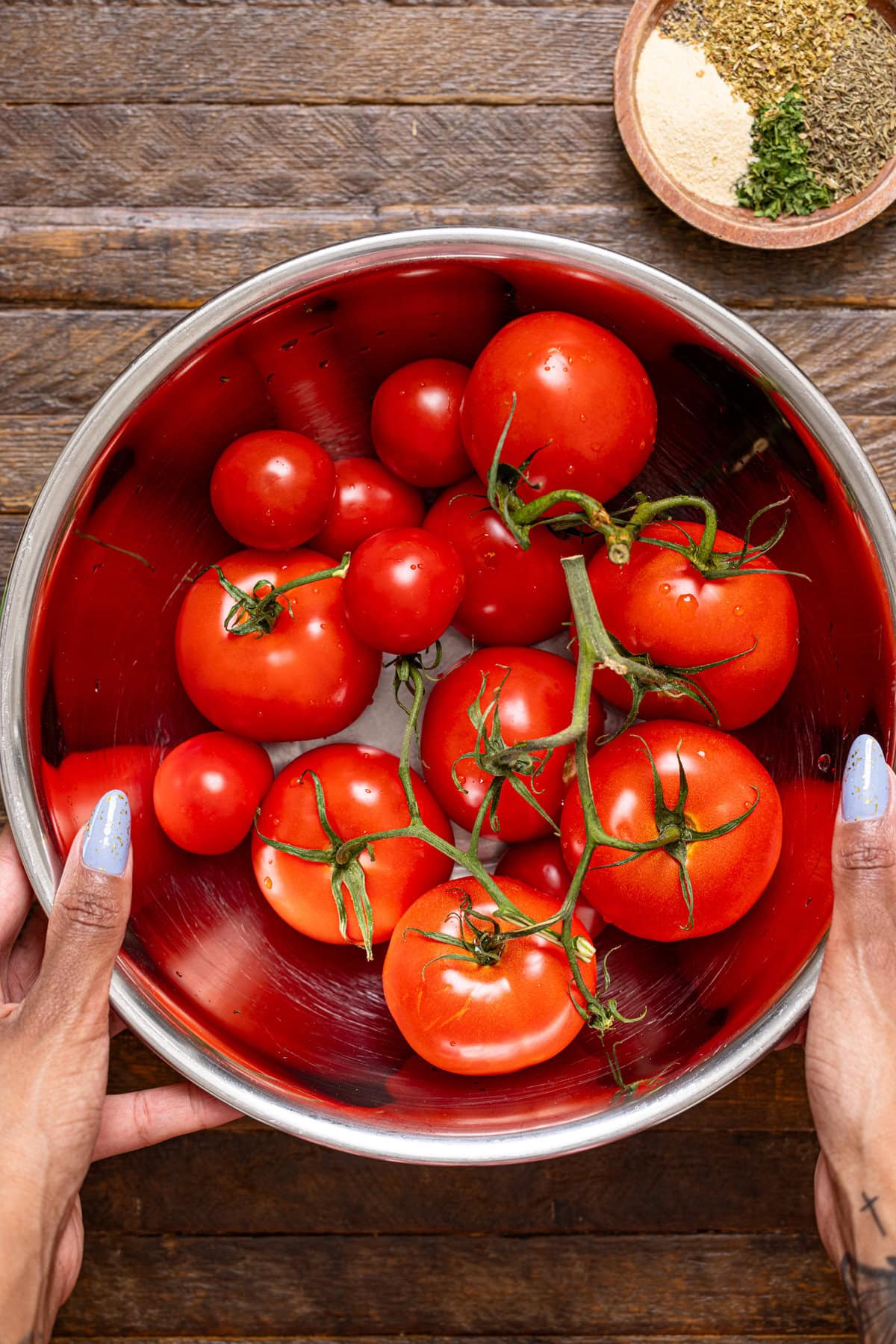 A silver bowl being held with tomatoes. 