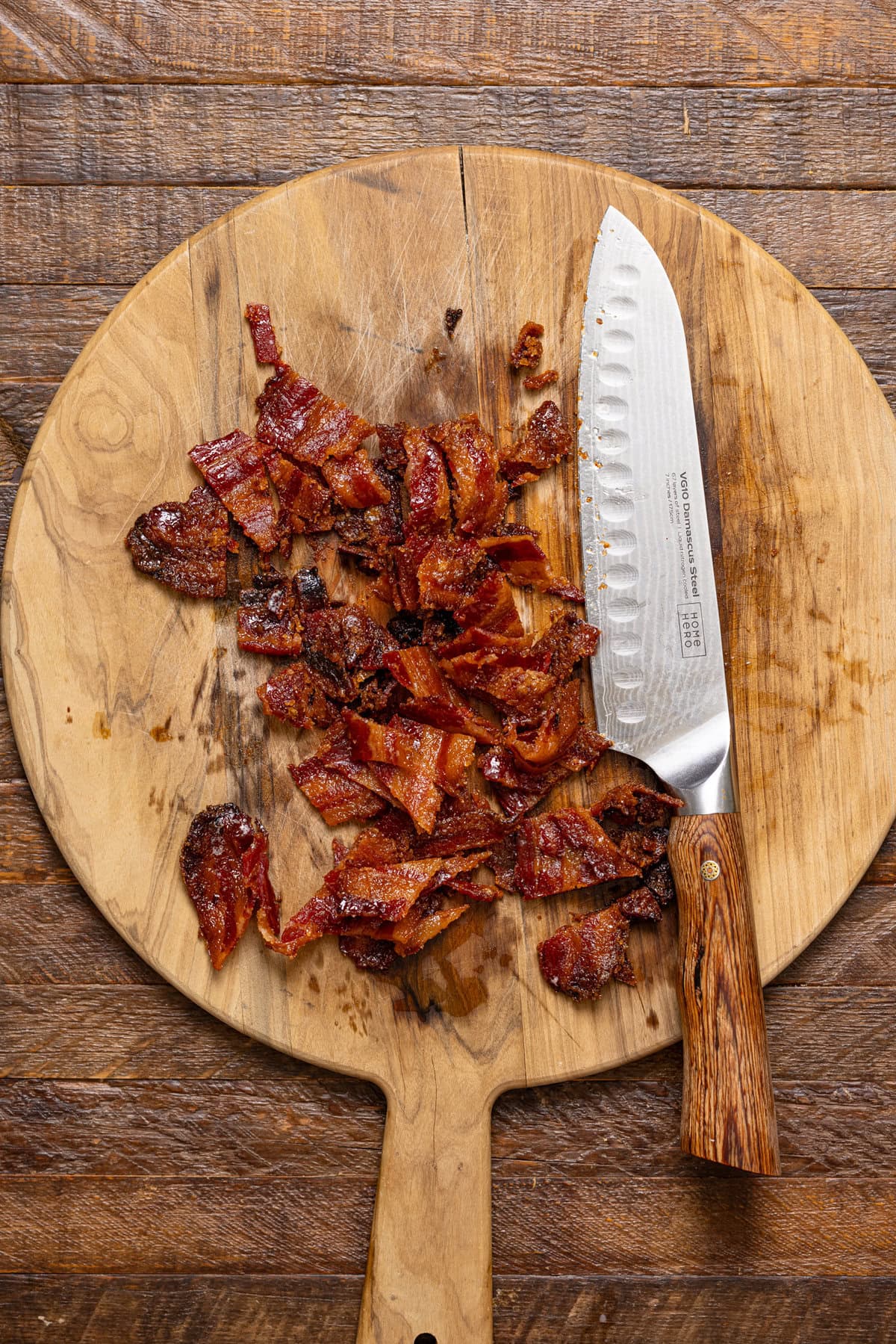 Chopped candied bacon on a cutting board with a knife.