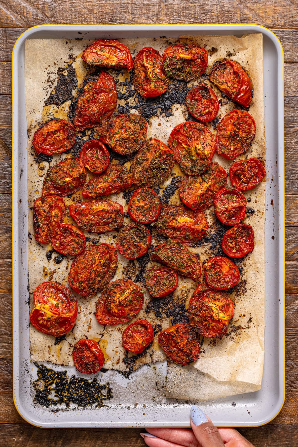 Roasted tomatoes on a baking sheet lined with parchment paper.