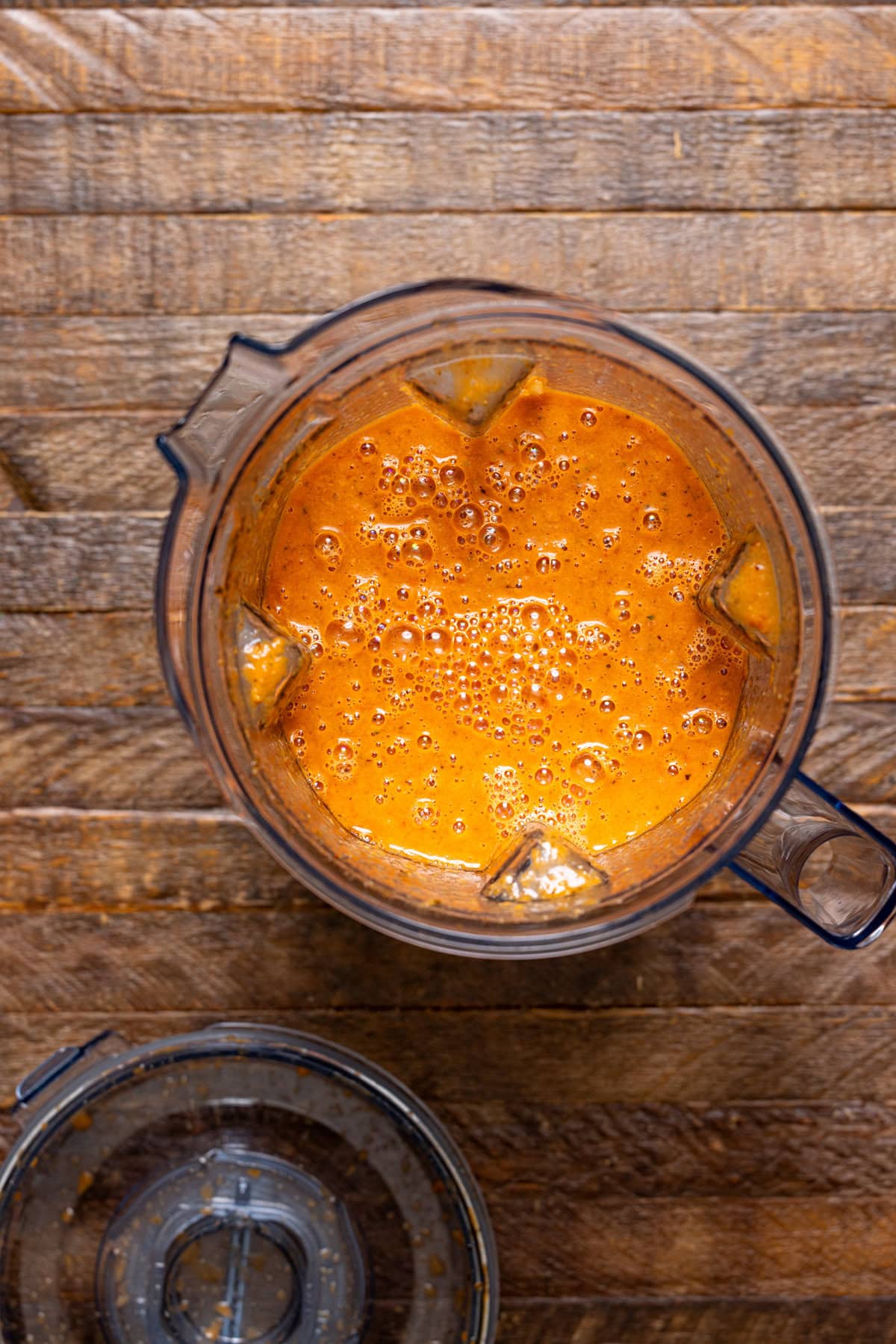 Bisque ingredients in a blender on a wood table.