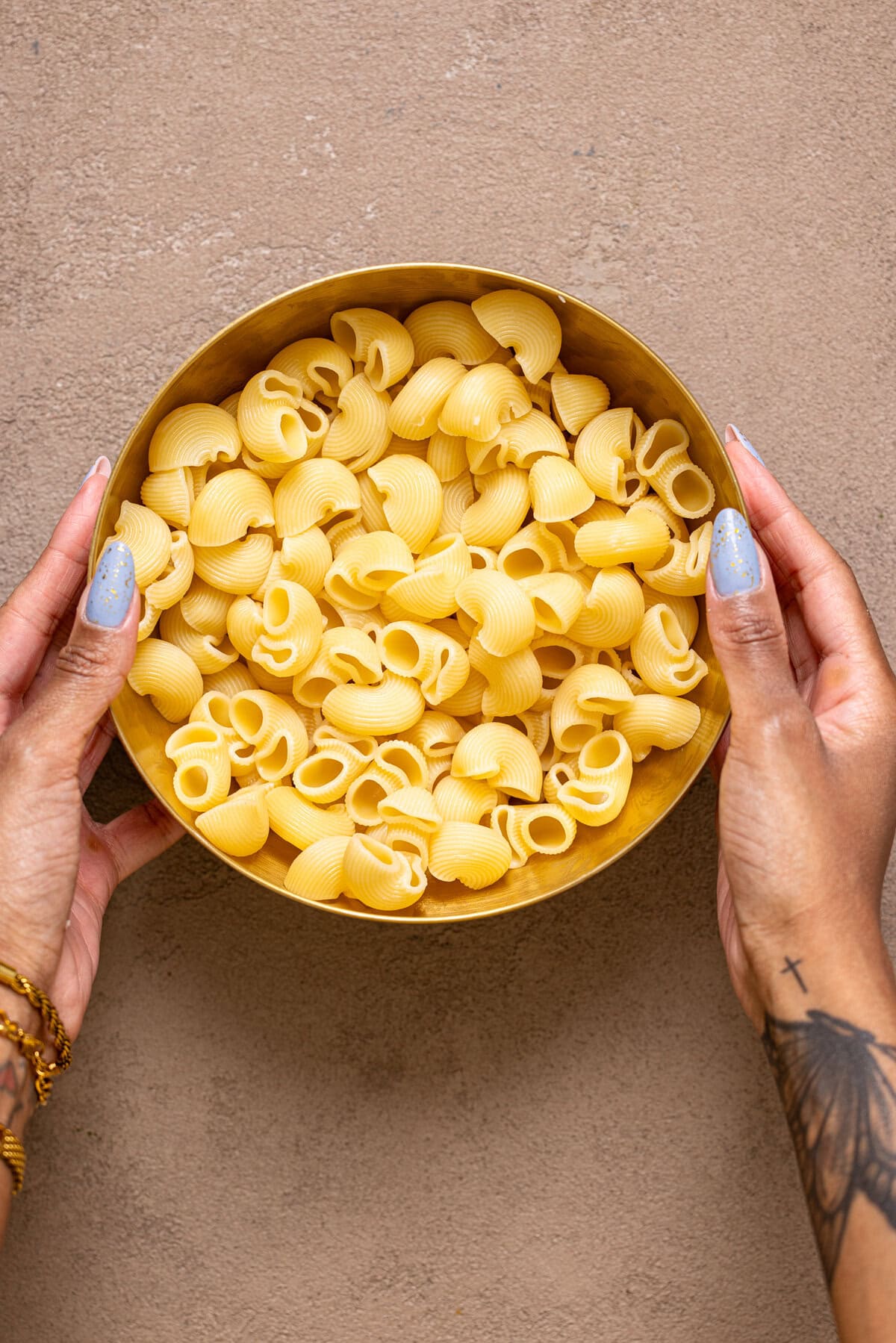 Cooked pasta in a bowl being held with hands.