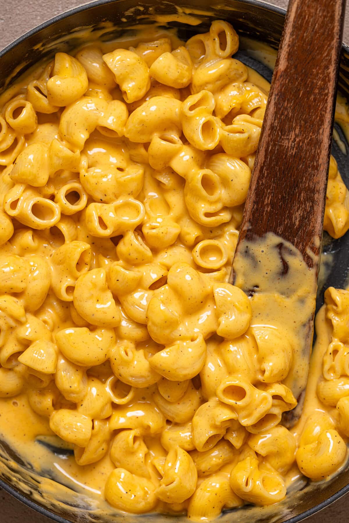 Mac and cheese in a skillet with a wooden spoon.