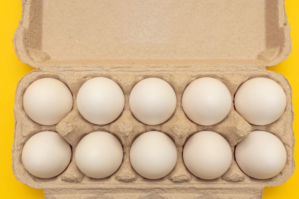 Carton of eggs on yellow background.