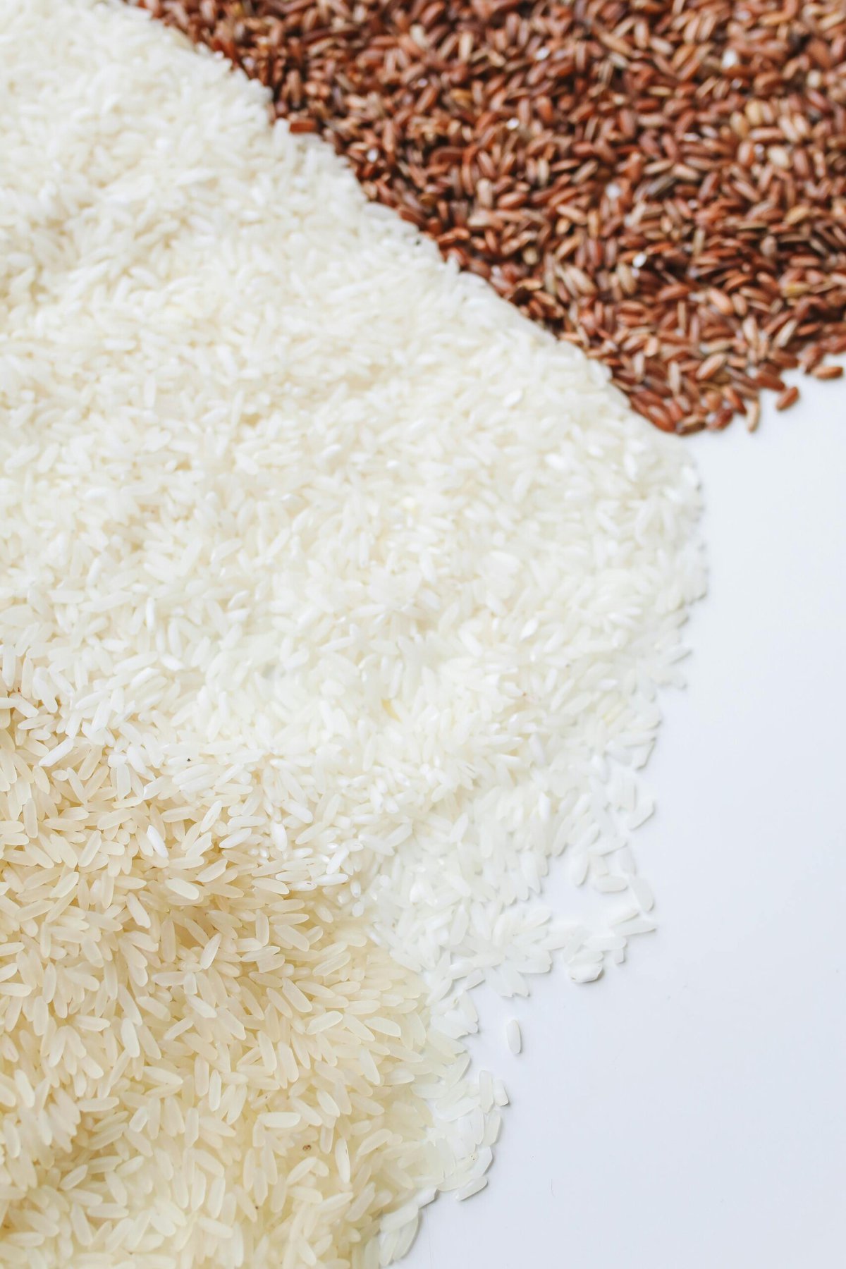 Brown, white and red rice on white background.