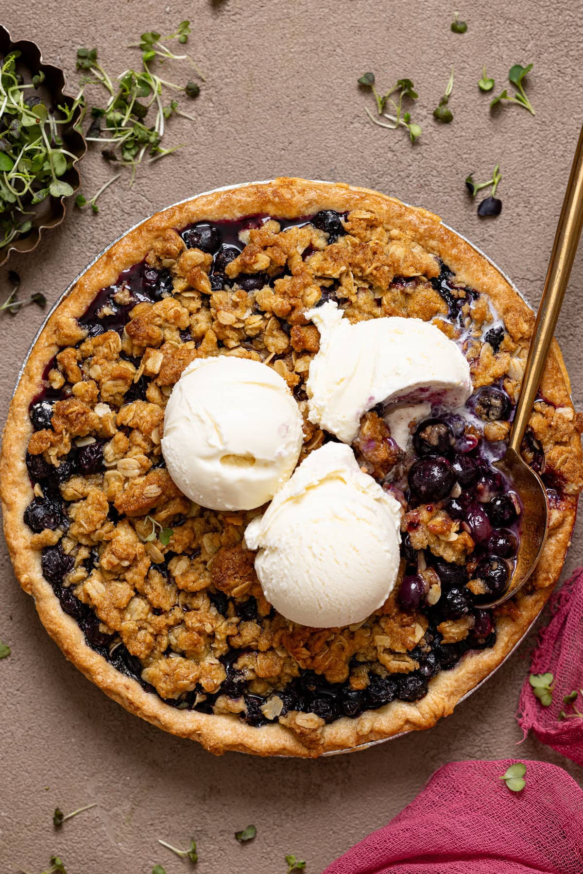 Blueberry pie topped with ice cream and a spoon.