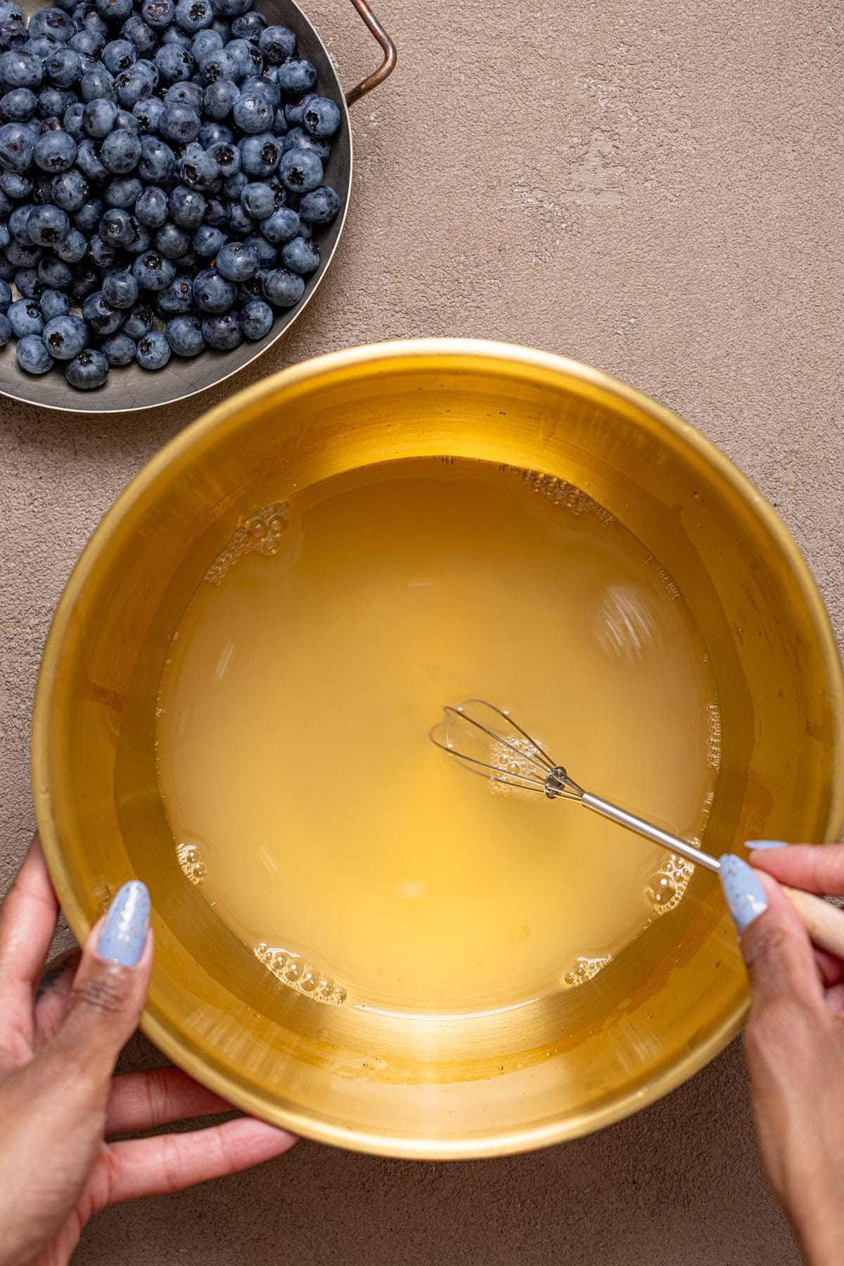 Lemonade being stirred in a gold bowl.