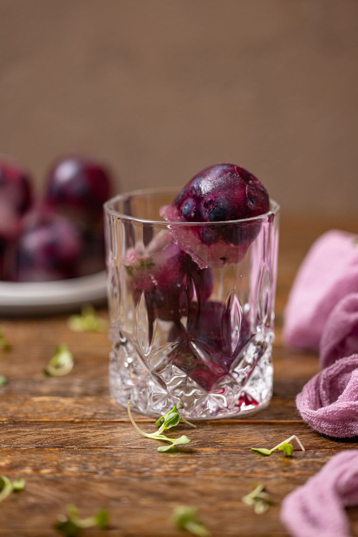 Blueberry ice cubes stacked in a glass.