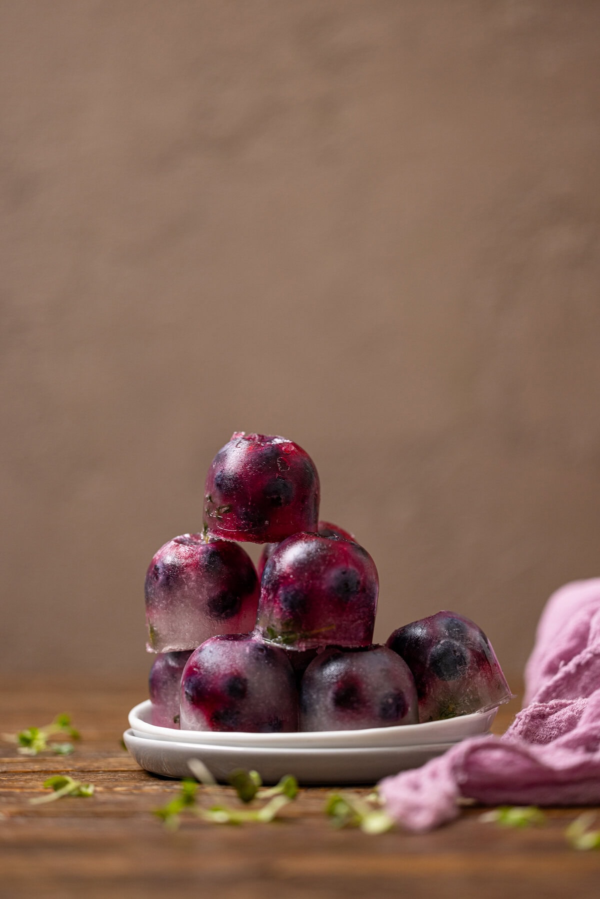 Blueberry thyme ice cubes stacked on plates.