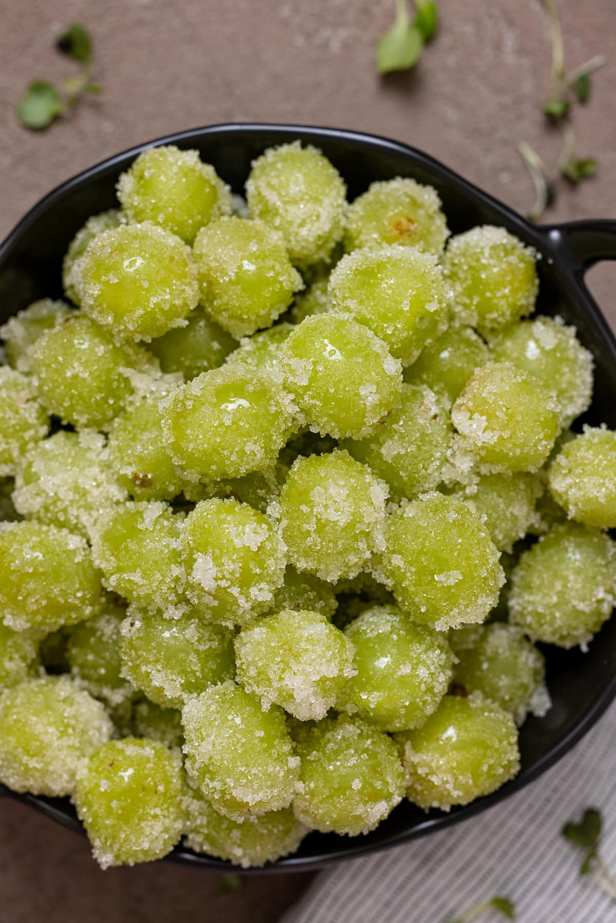 Up close shot of candied grapes in a black bowl.