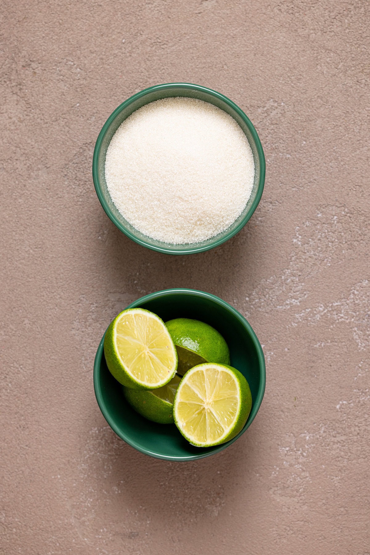 Ingredients in green bowls on a greyish-brown table.