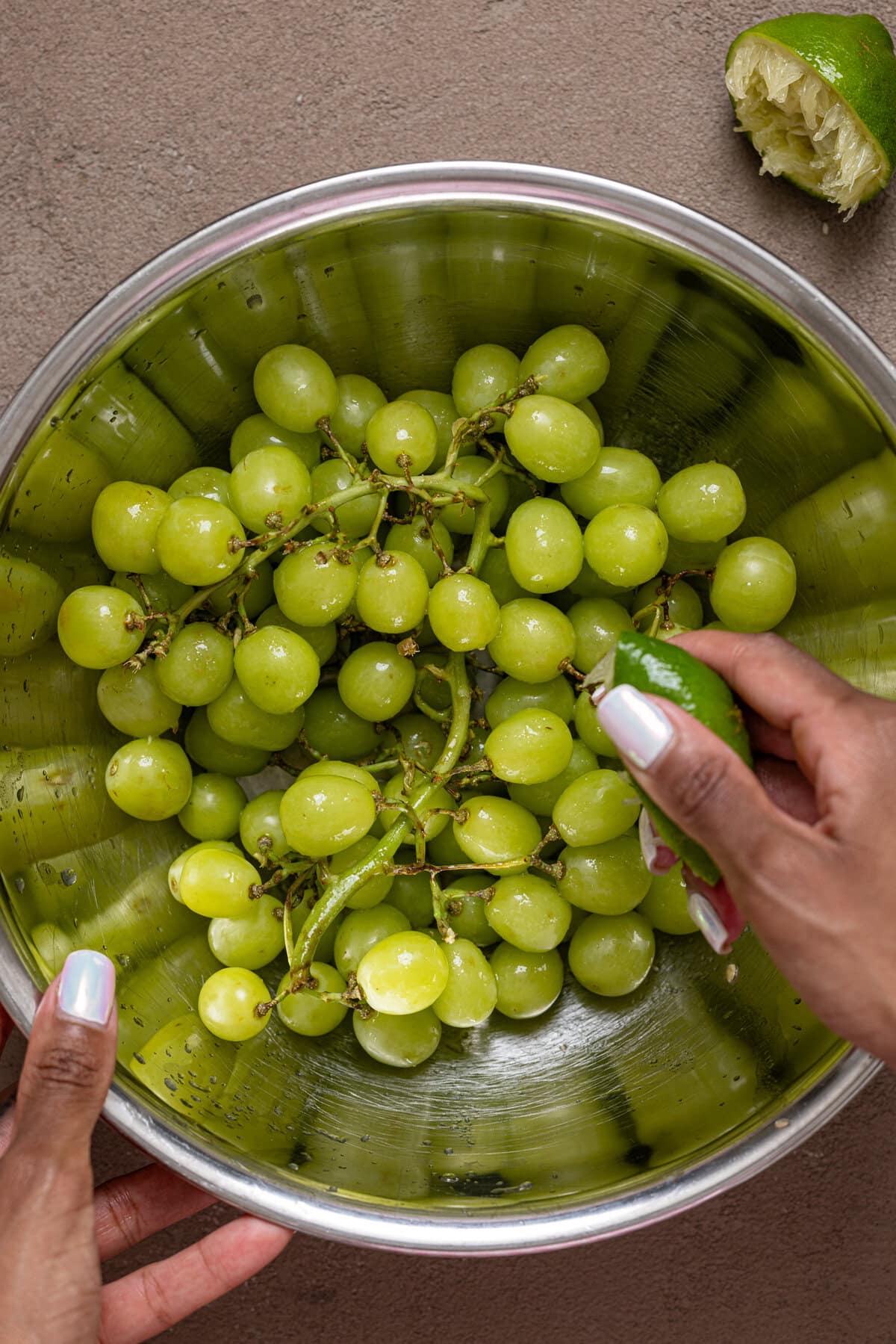 Green grapes in a silver bowl being held.