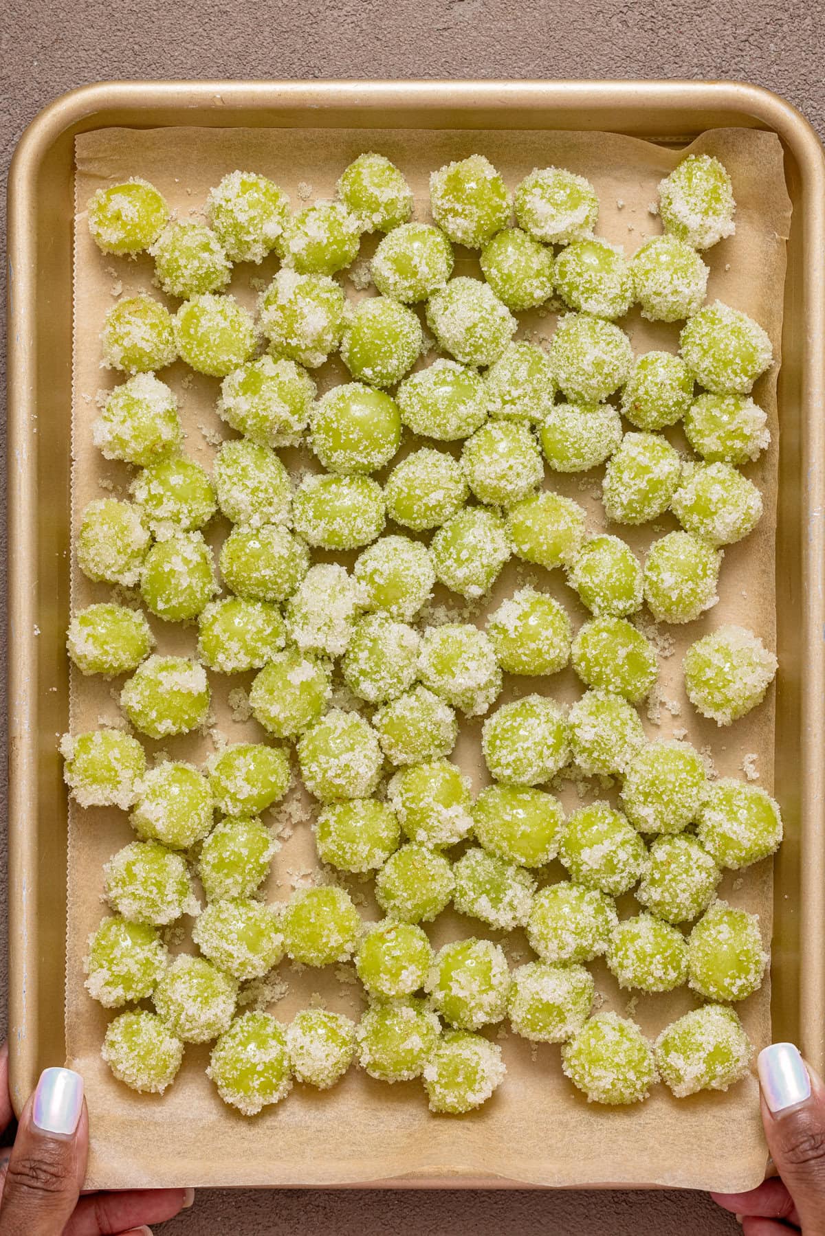 Coated grapes on a baking sheet with parchment paper.