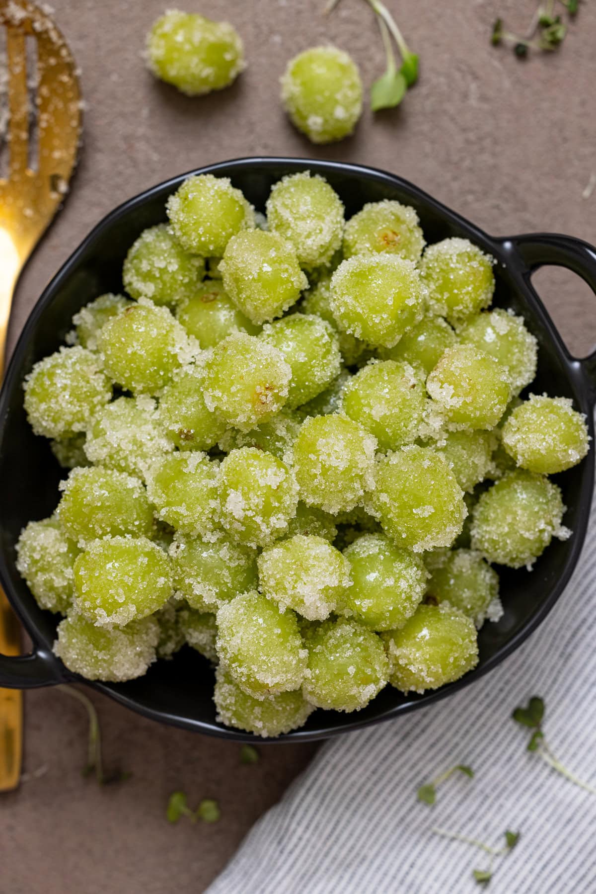 Coated candied grapes in a bowl with a spoon.