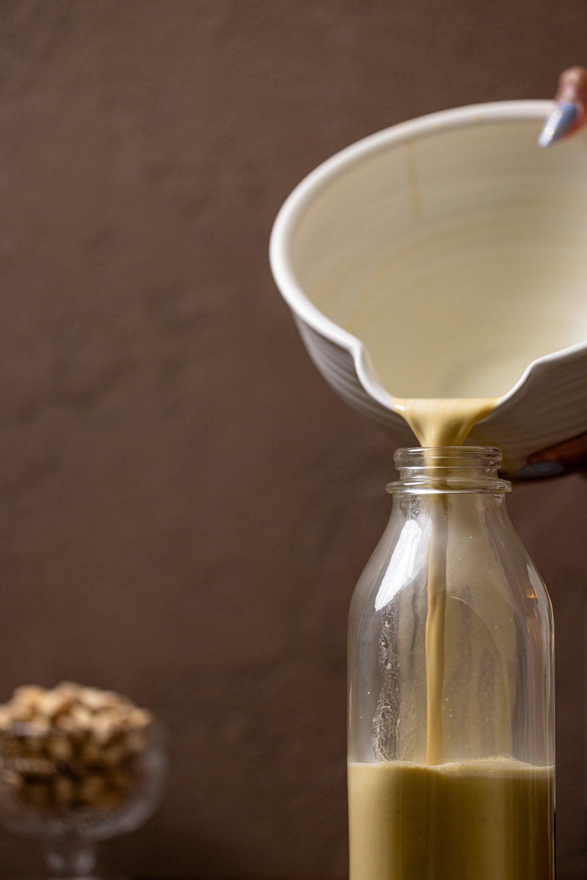 Pistachio milk being poured into a glass bottle.