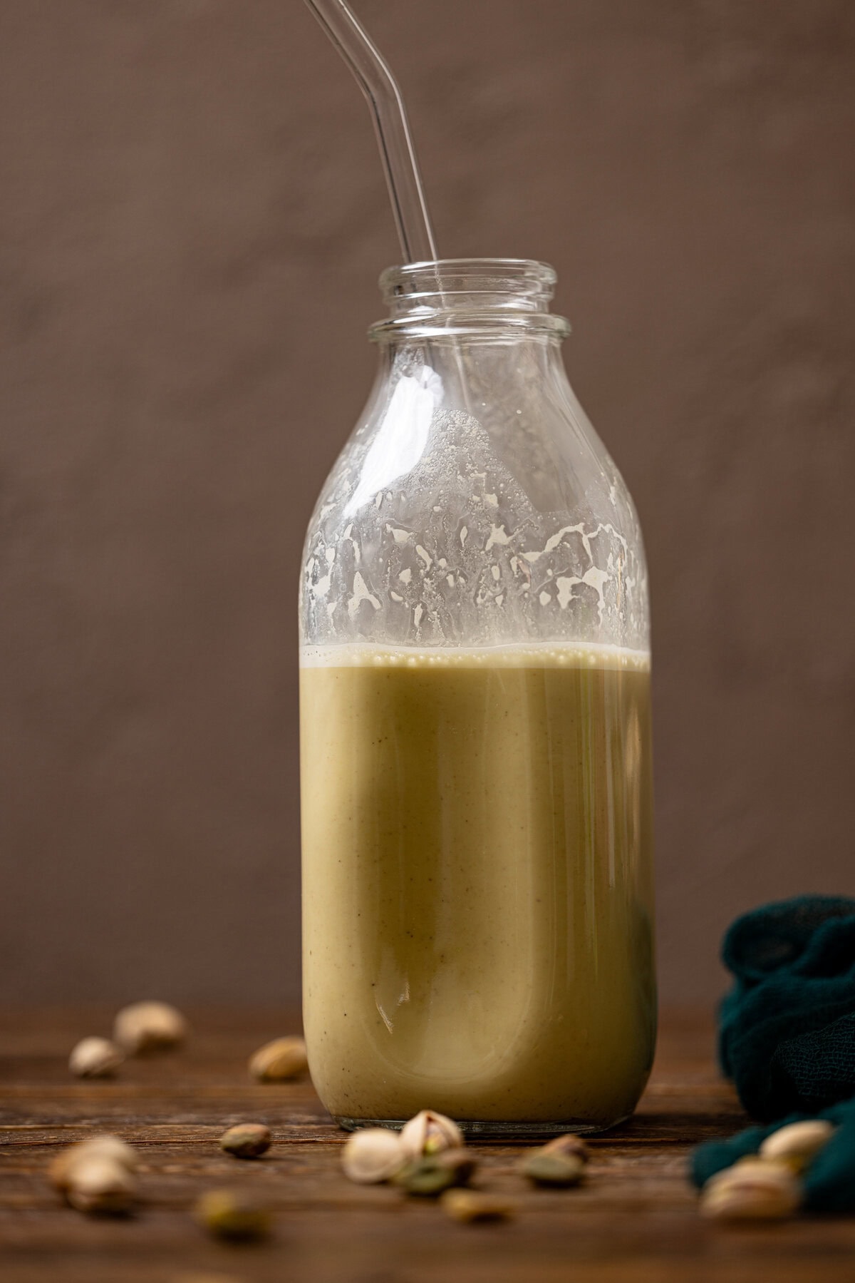 Up close shot of pistachio milk in a glass bottle.