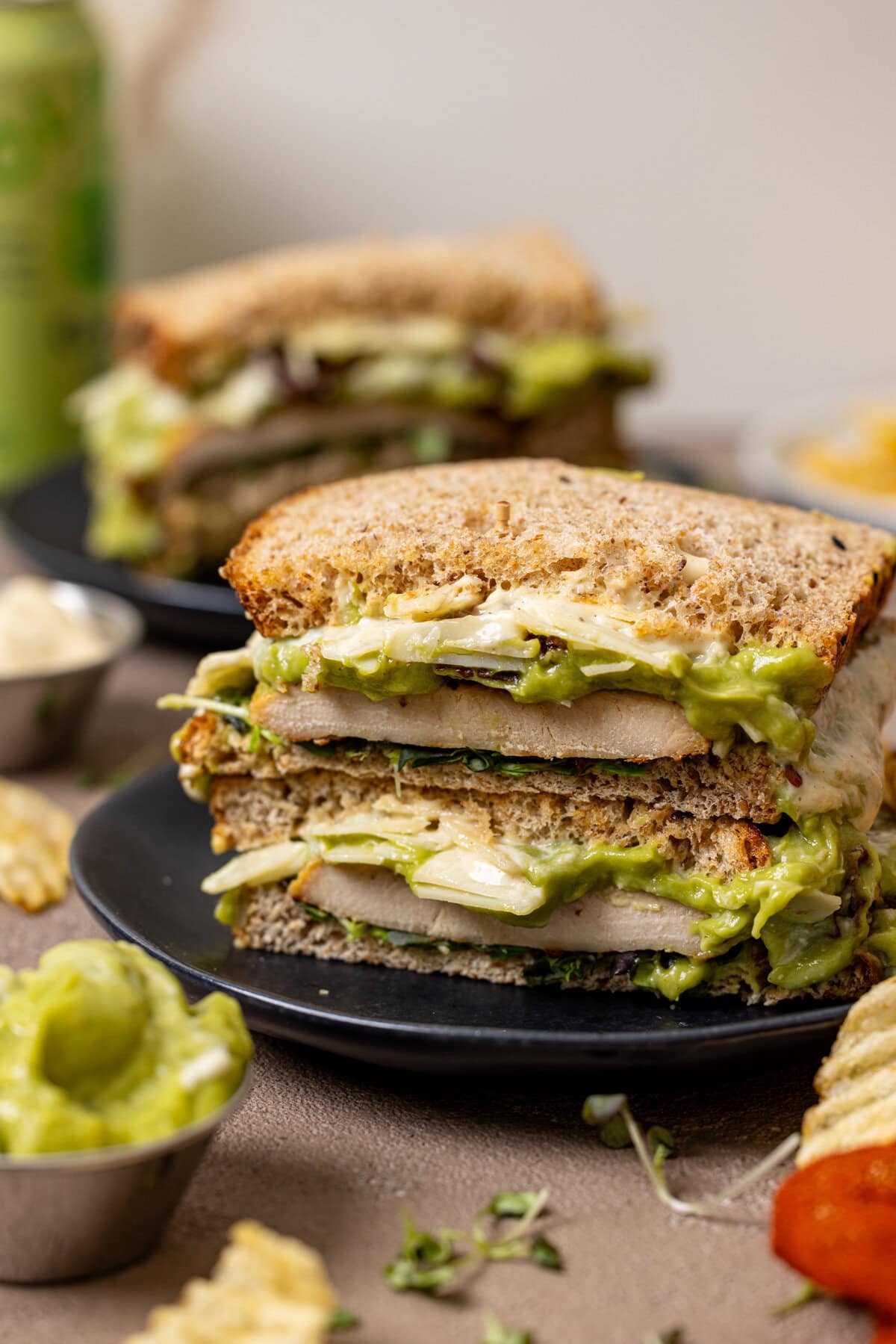 Sandwiches stacked on black plates with garnish and a drink.