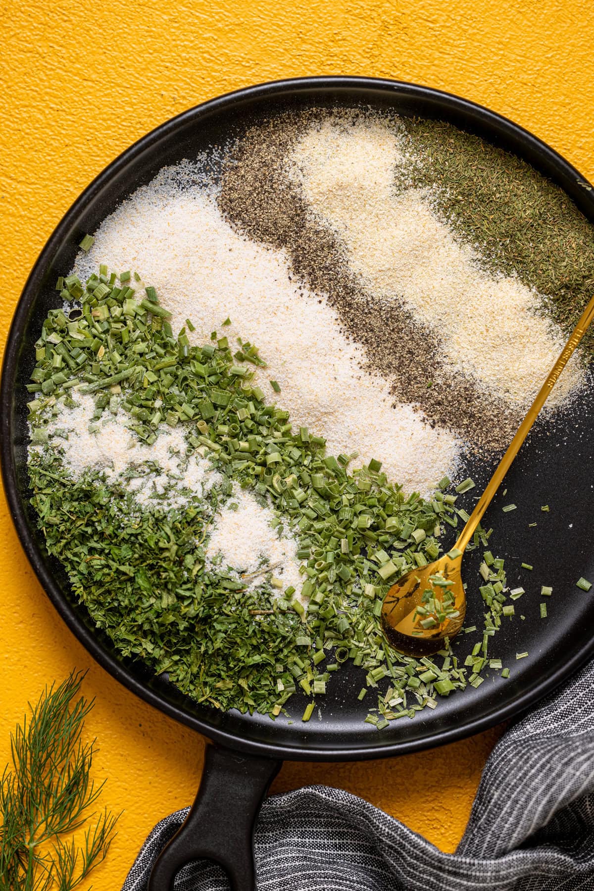 Ranch seasoning mix on a black plate with a gold spoon.