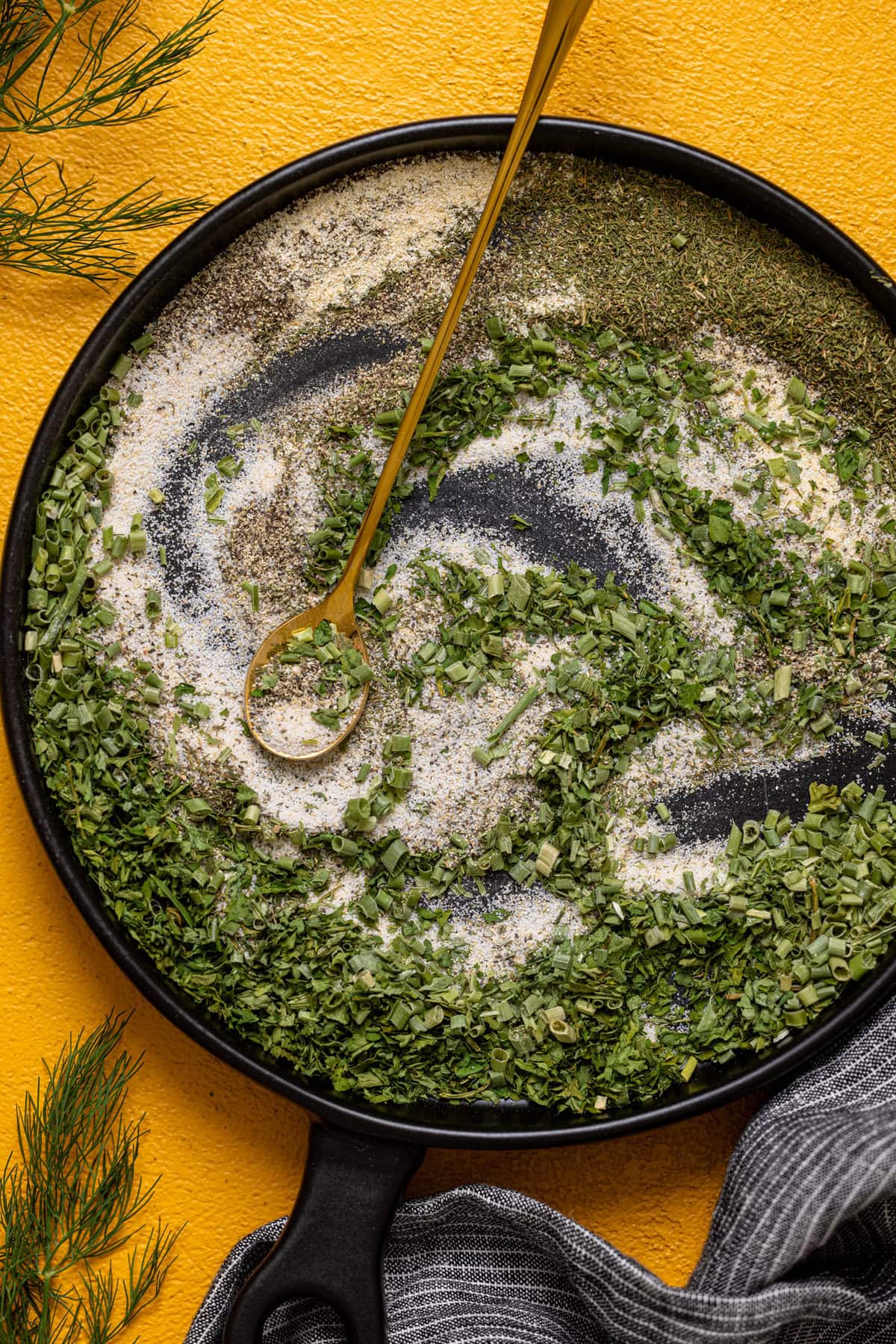 Ranch seasoning mix on a black plate on a yellow table with a spoon.