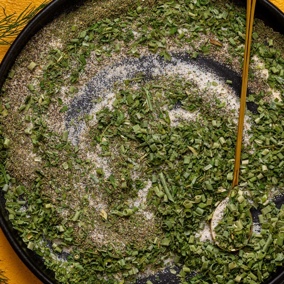 Up close shot of ranch seasoning mix on a black plate with a spoon.