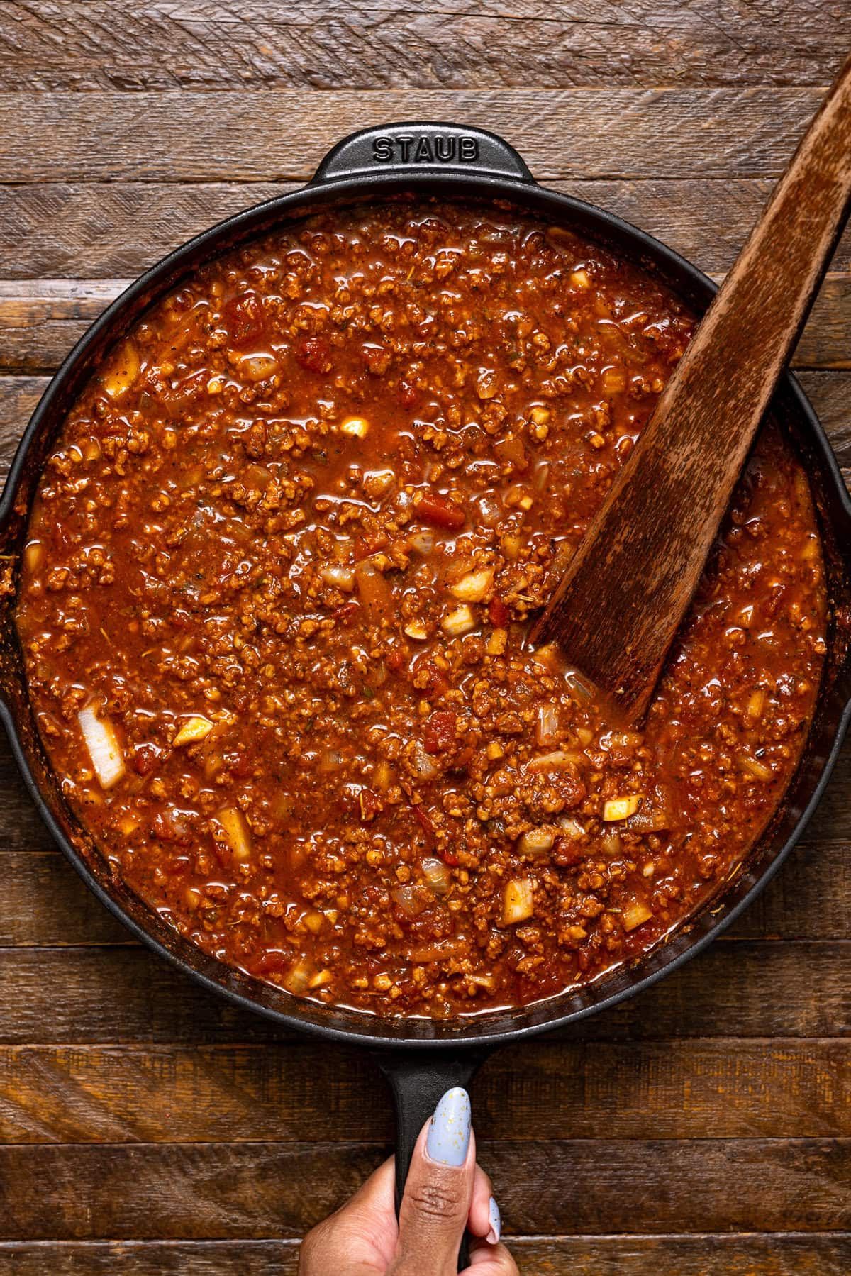 Cooked plant-based meat in a black skillet with a wooden spoon.