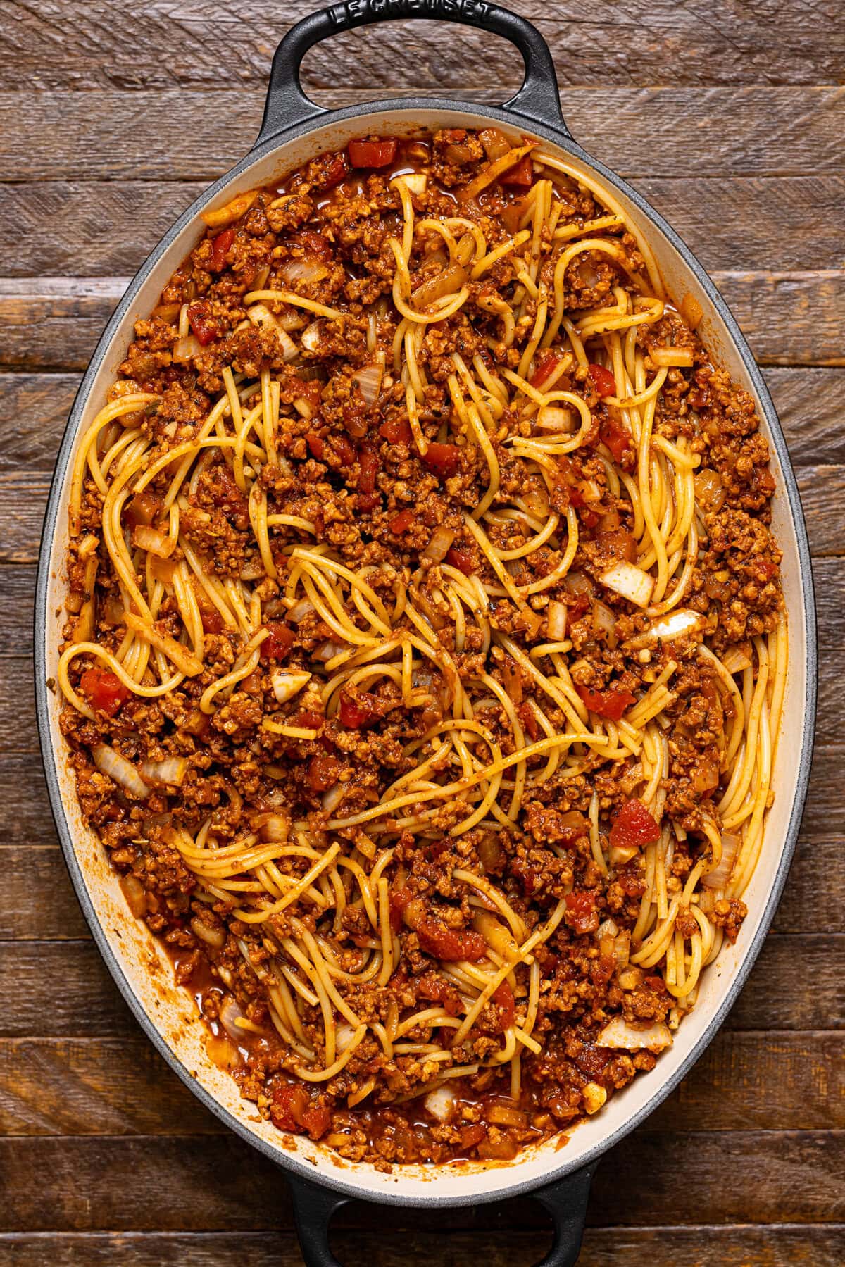 Ingredients layered in a baking dish on a brown wood table.