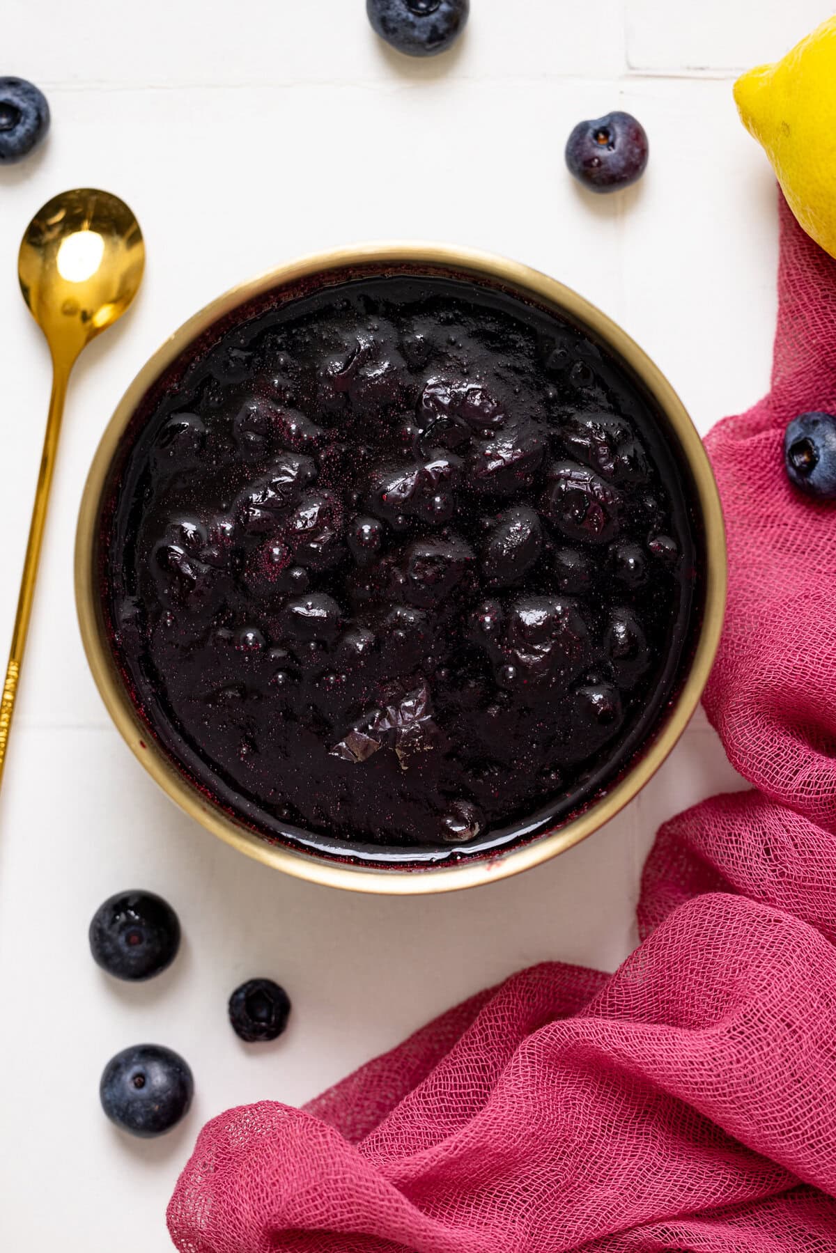 A bowl of blueberry compote with blueberries and a spoon.