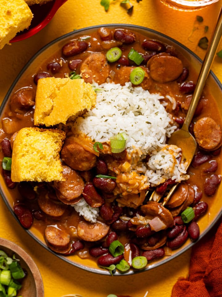 Up close shot of red beans and rice in a plate with a fork and cornbread.