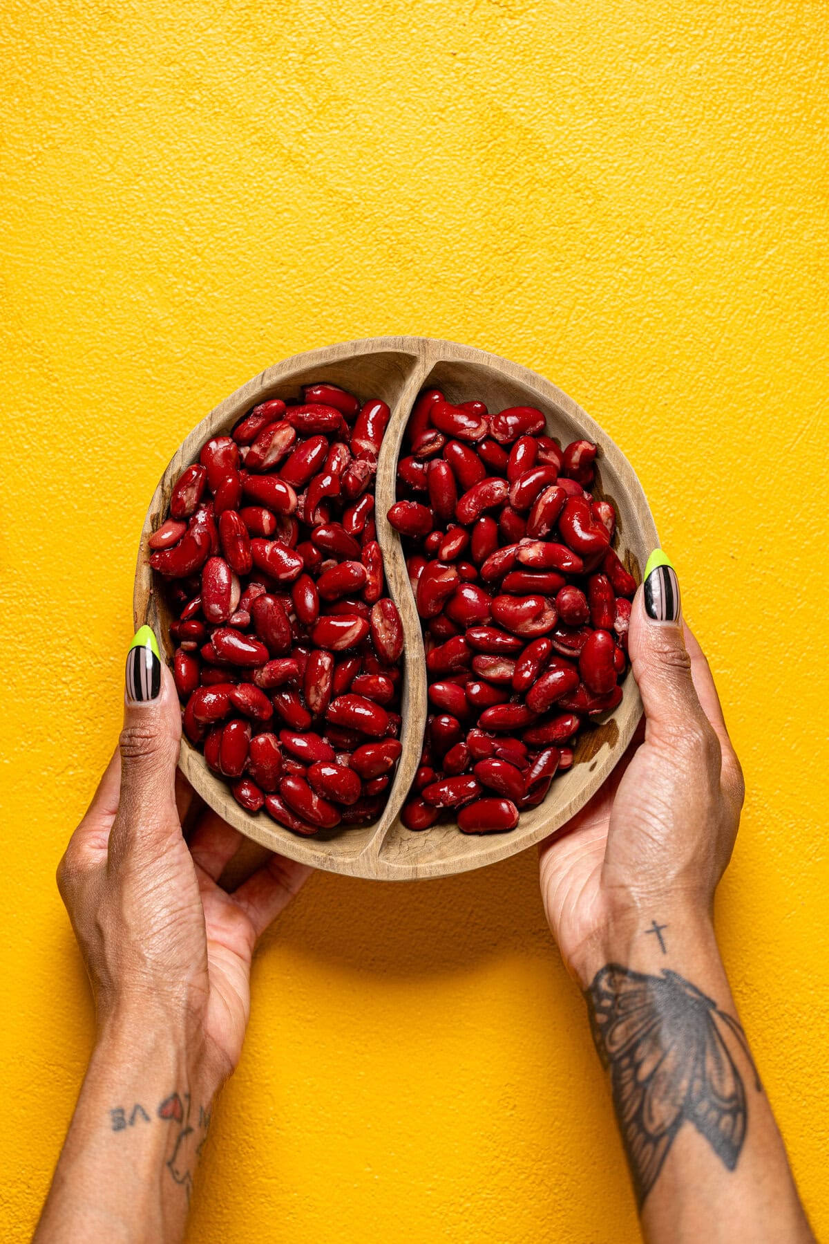 A bowl of kidney beans being held by woman hands.