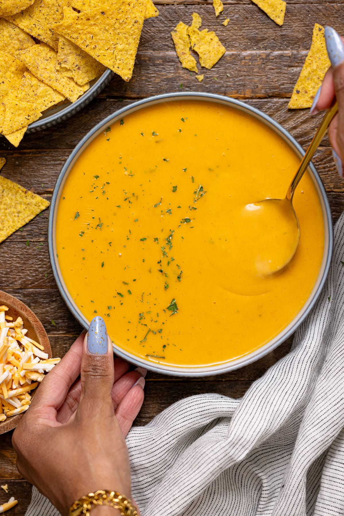 Bowl of nacho cheese being held with a hand and a spoon.