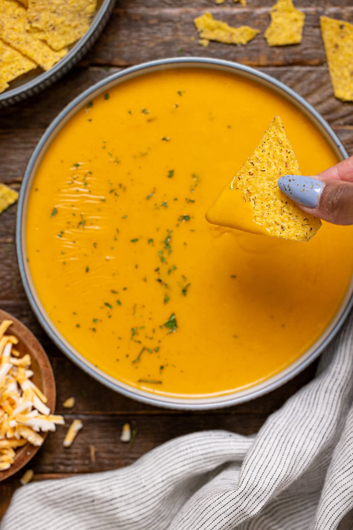 Tortilla chip being dipped in nacho cheese.