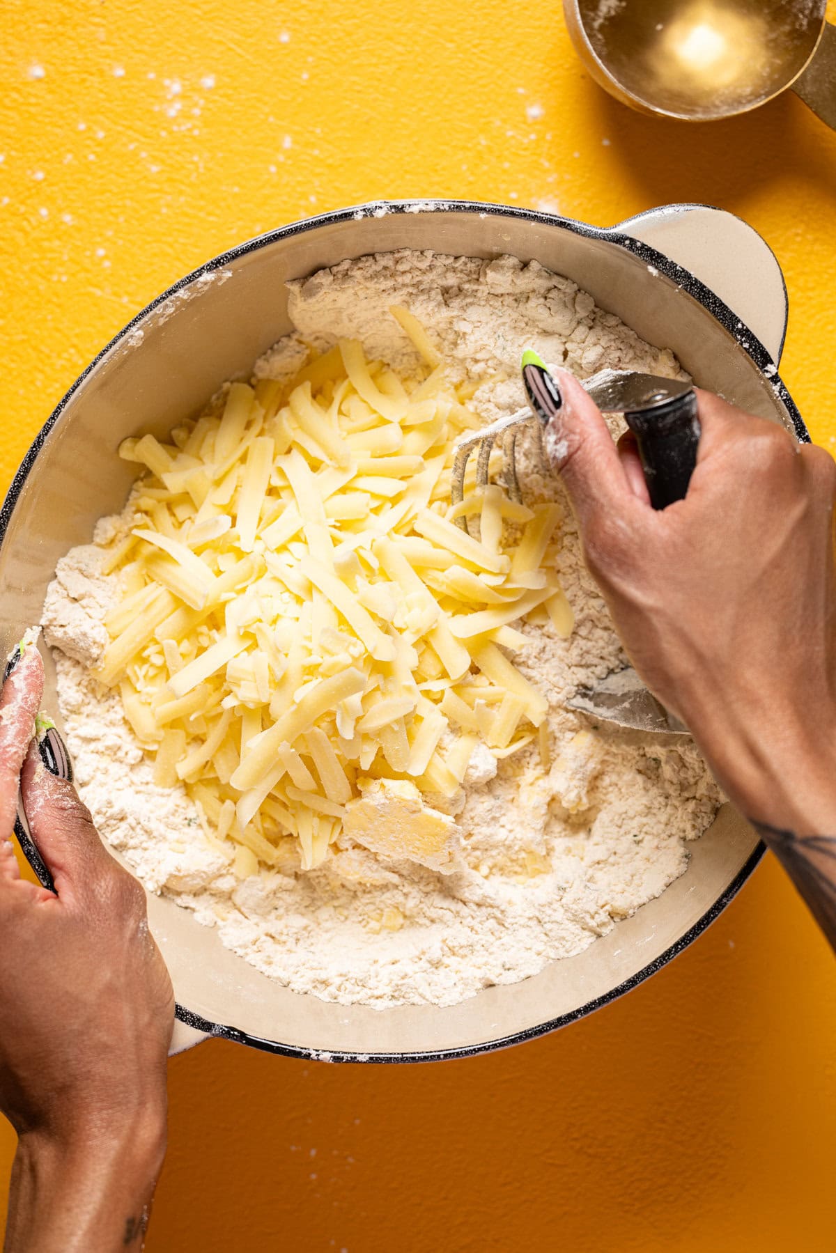 Ingredients in a bowl being stirred together on a yellow table.