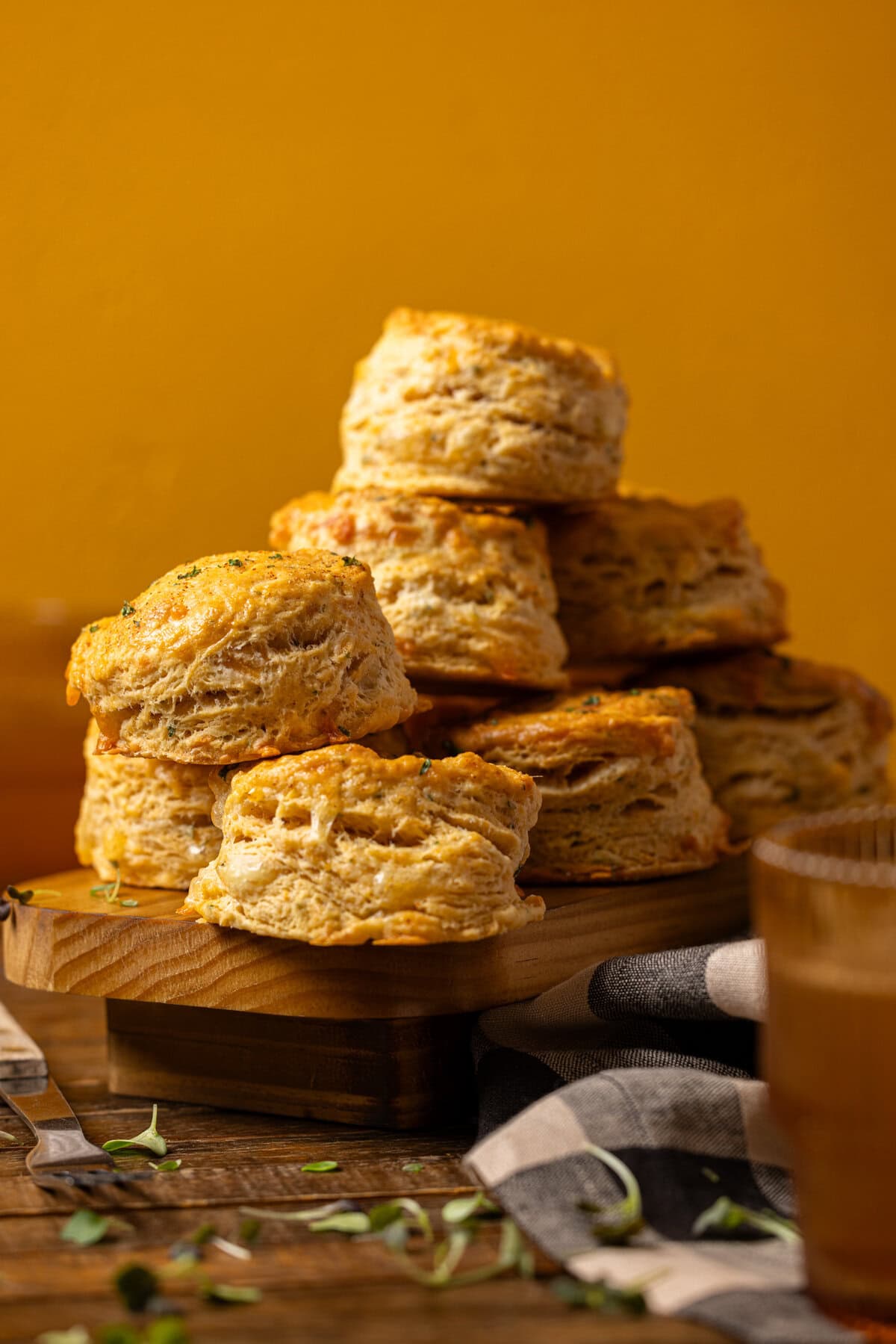 Stack of biscuits on a wood platter with a drink.