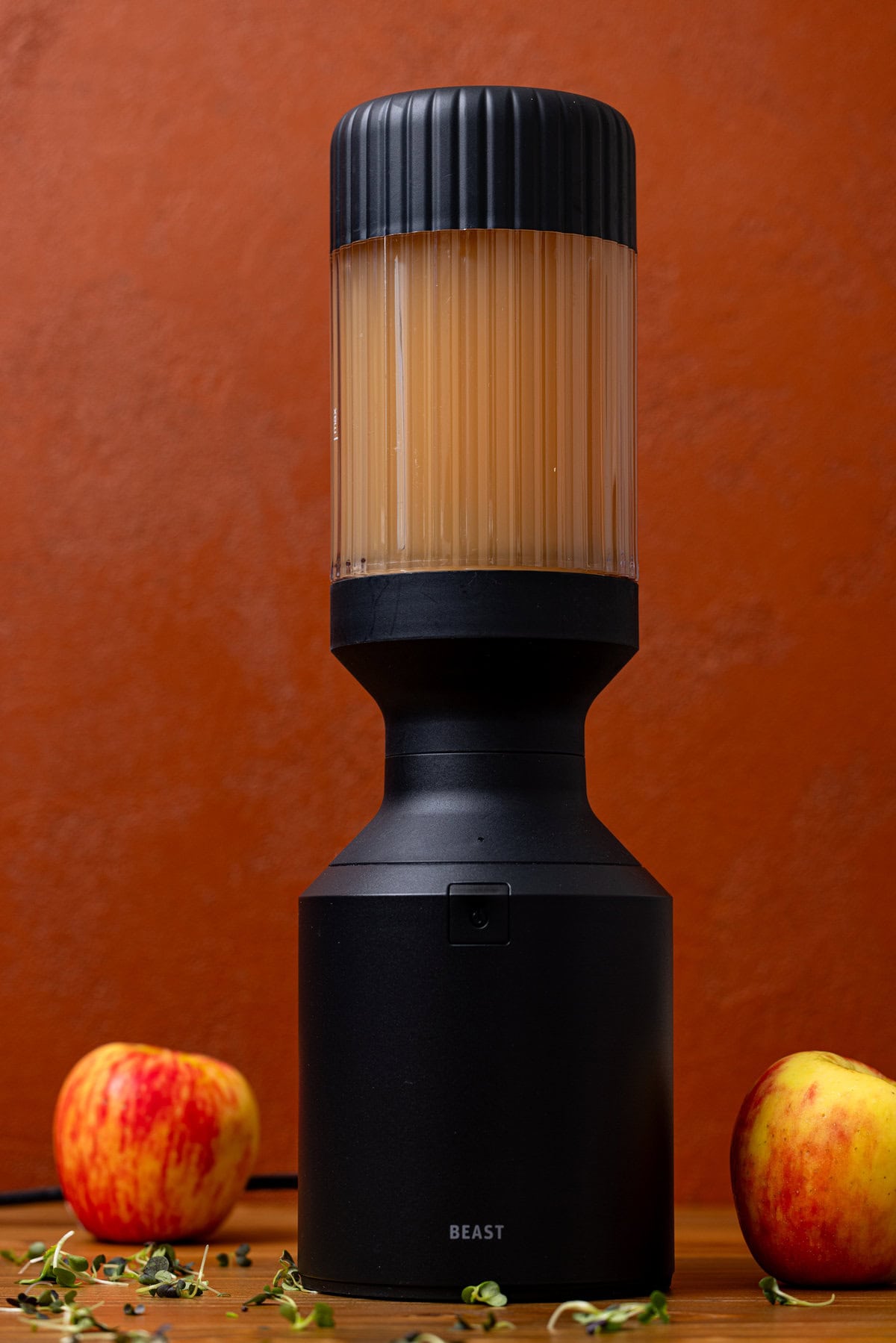 Fresh apple juice in a black blender with two apples.