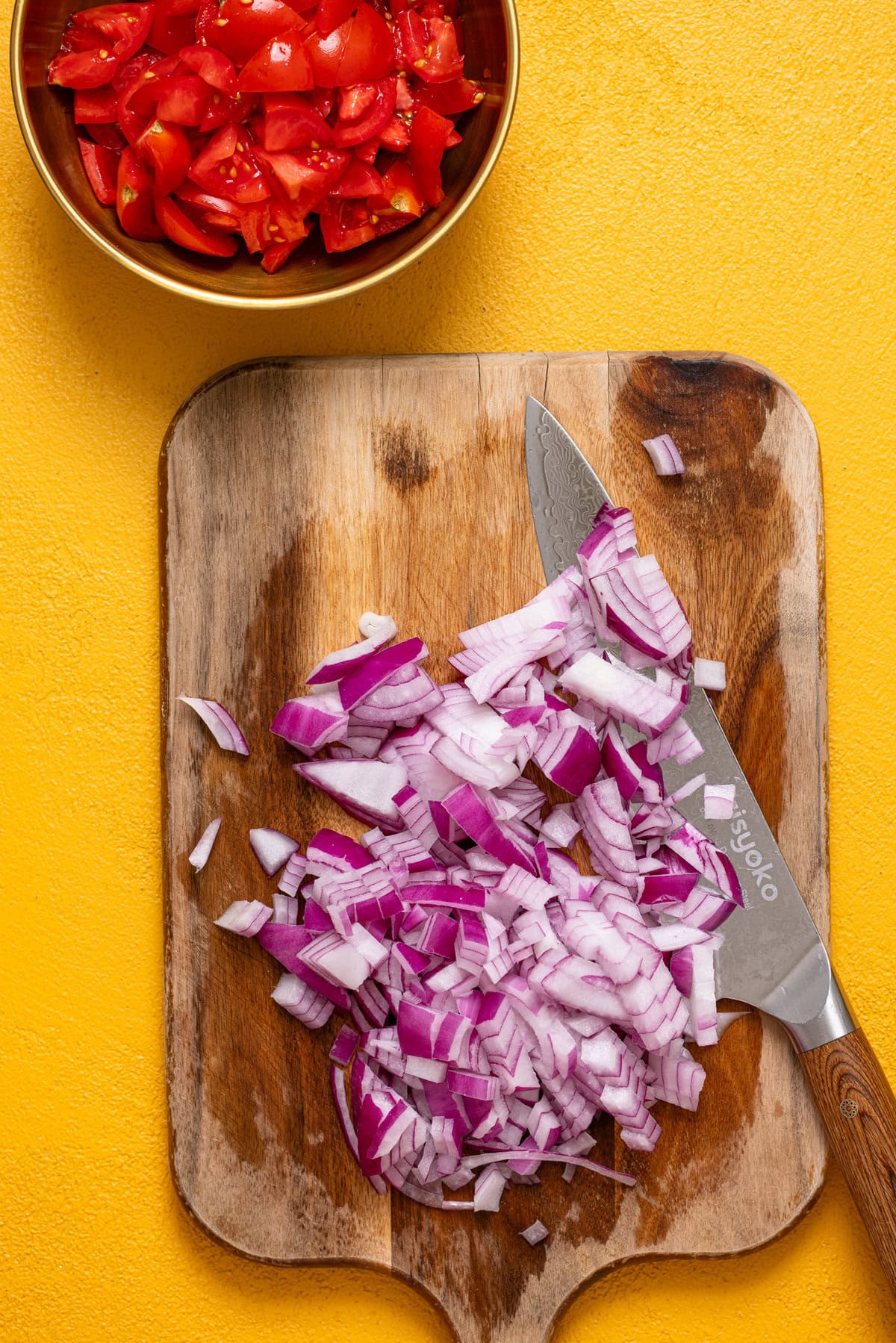 Chopped veggies on a cutting board with a knife.