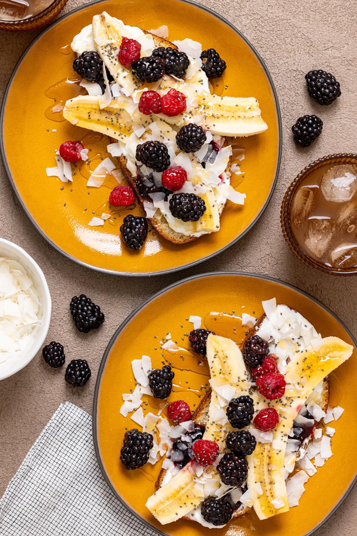 Two plates with breakfast toast, ingredients, and a drink.