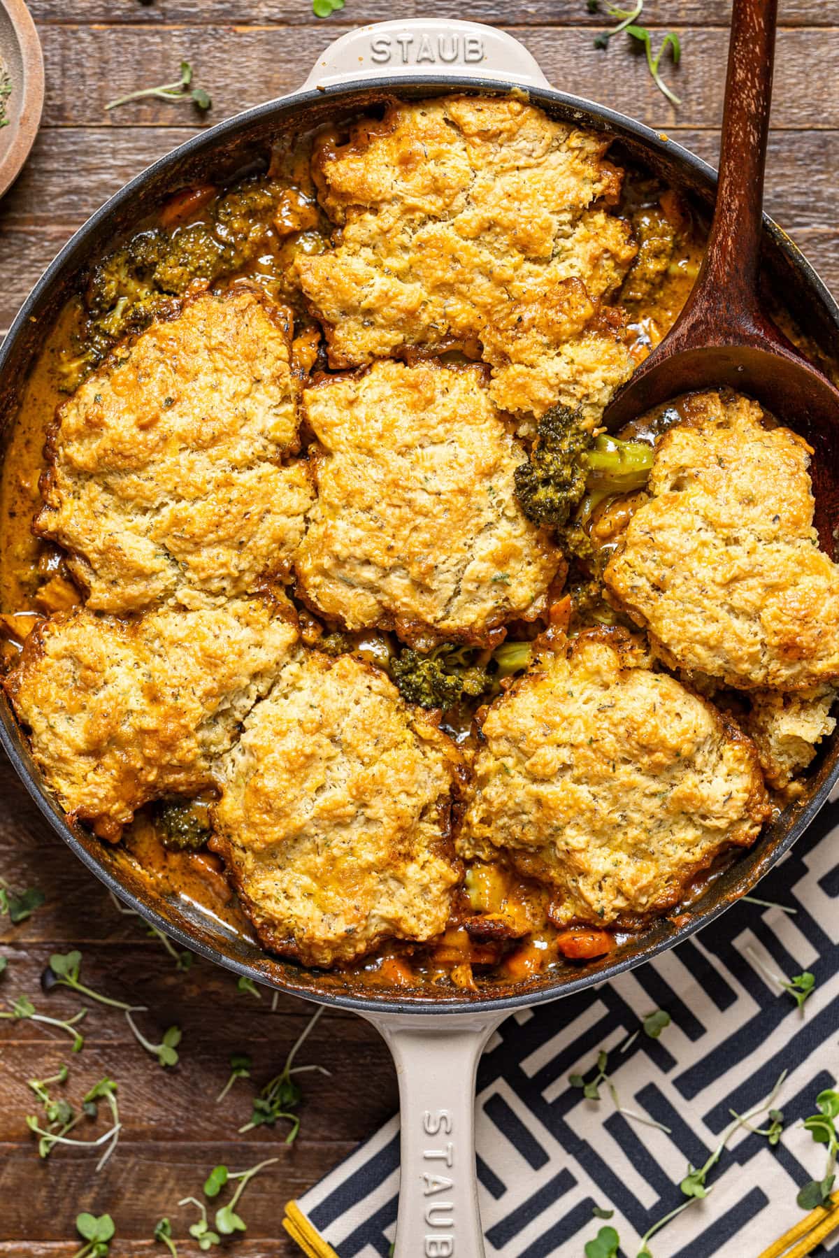 Up close shot of broccoli cheddar pot pie in a skillet with a wooden spoon.