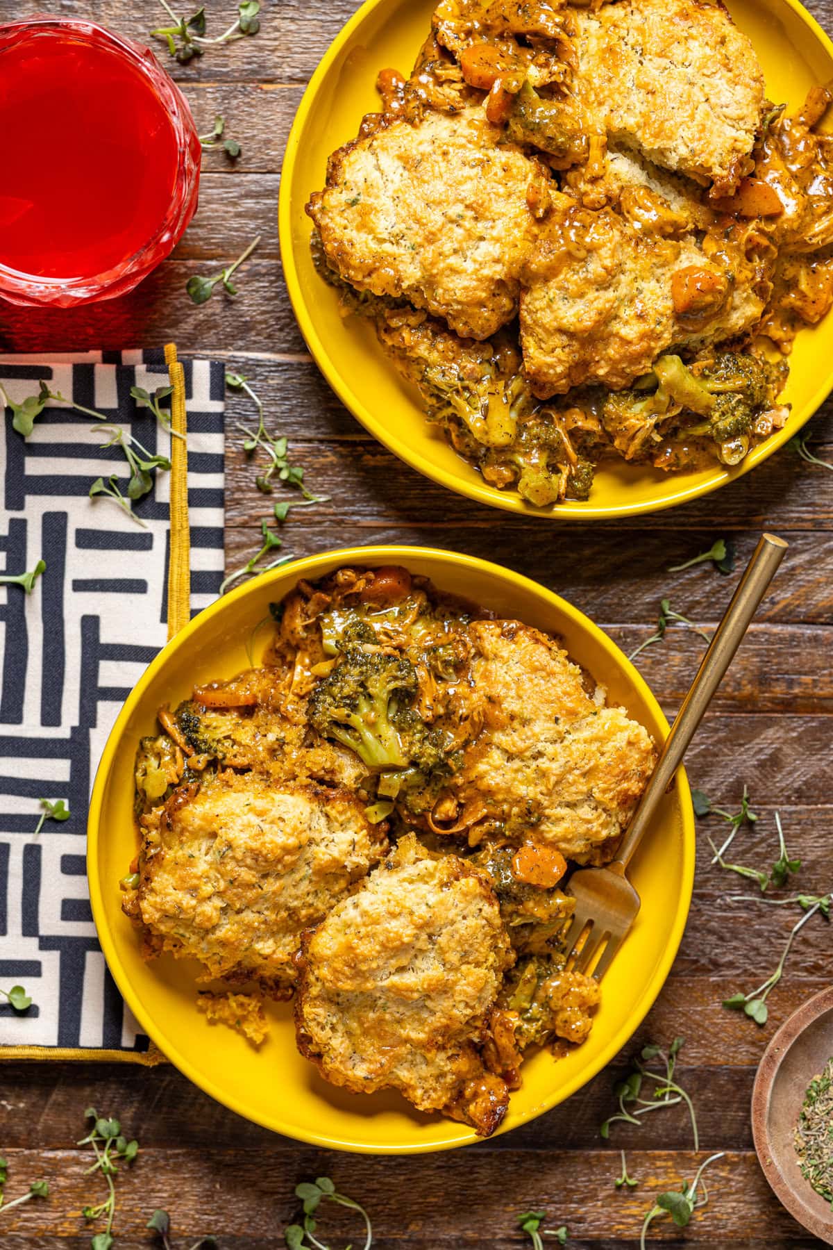 Two plates with broccoli cheddar pot pie with a fork and drink.