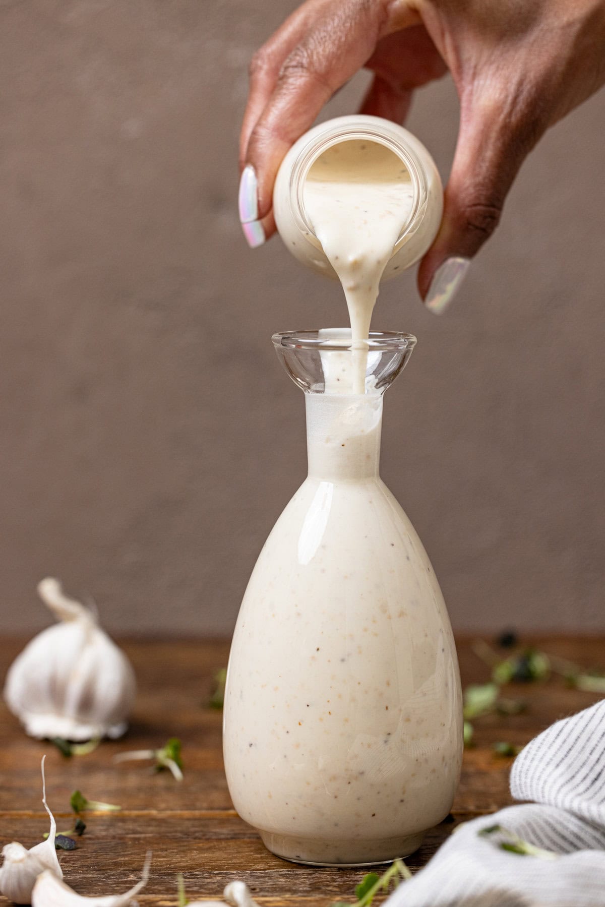 Image of creamy dressing being poured in a bottle with hands.