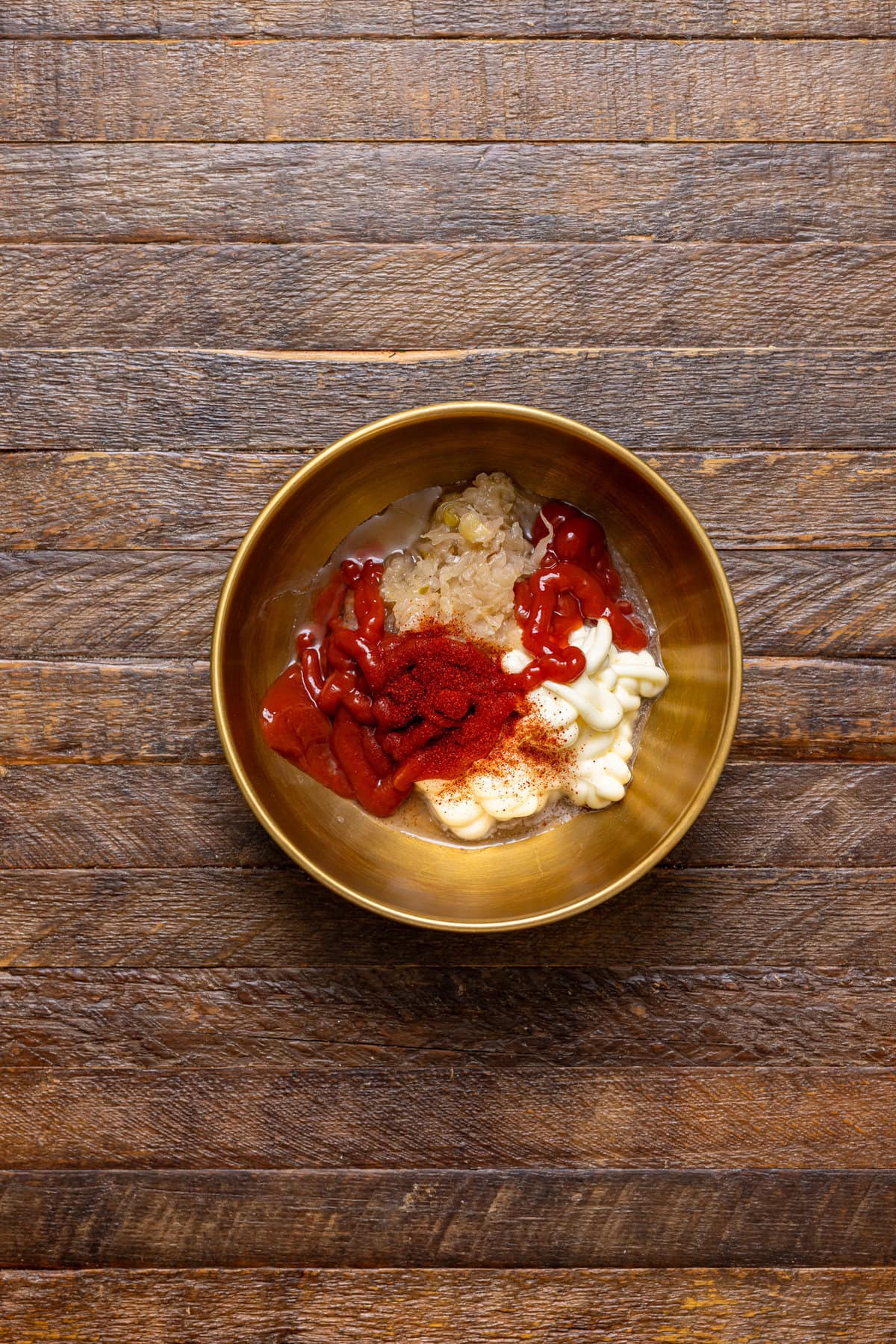 Ingredients in a gold bowl on a brown wood table.