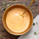 Dressing in a bowl on a brown wood table with a spoon.