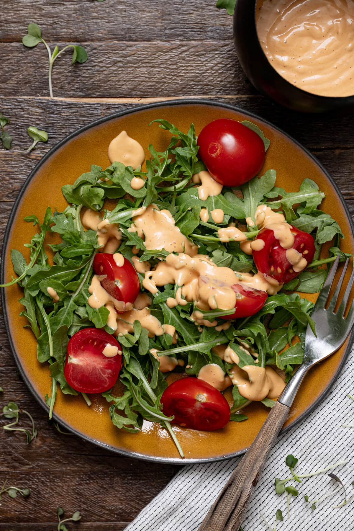 Up close shot of salad with dressing on a plate with a fork.