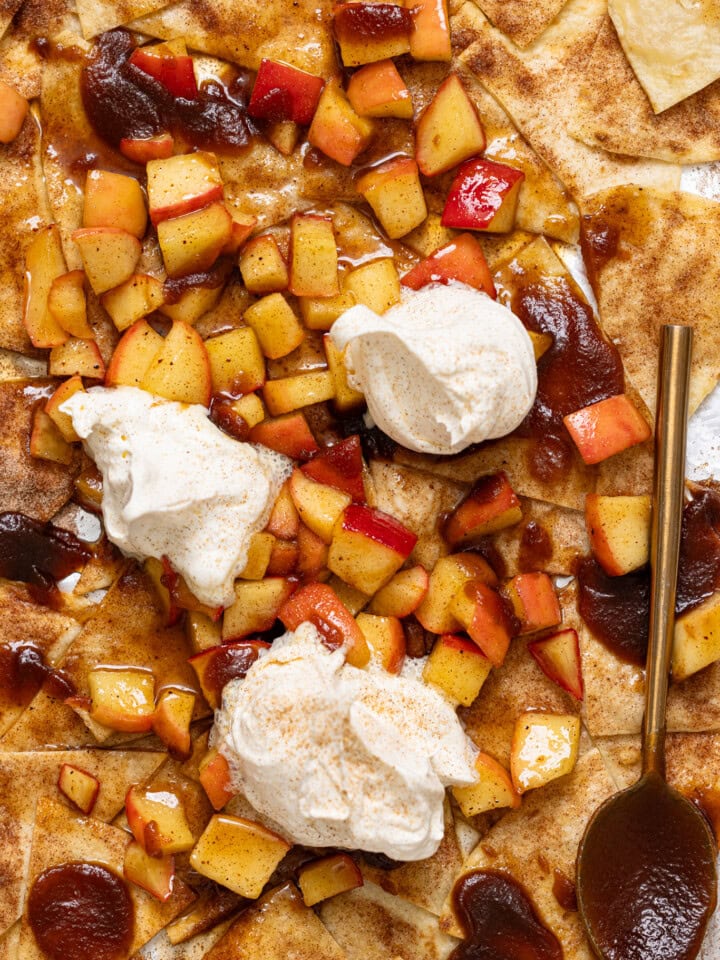 Up close shot of dessert nachos with whipped cream and a spoon.