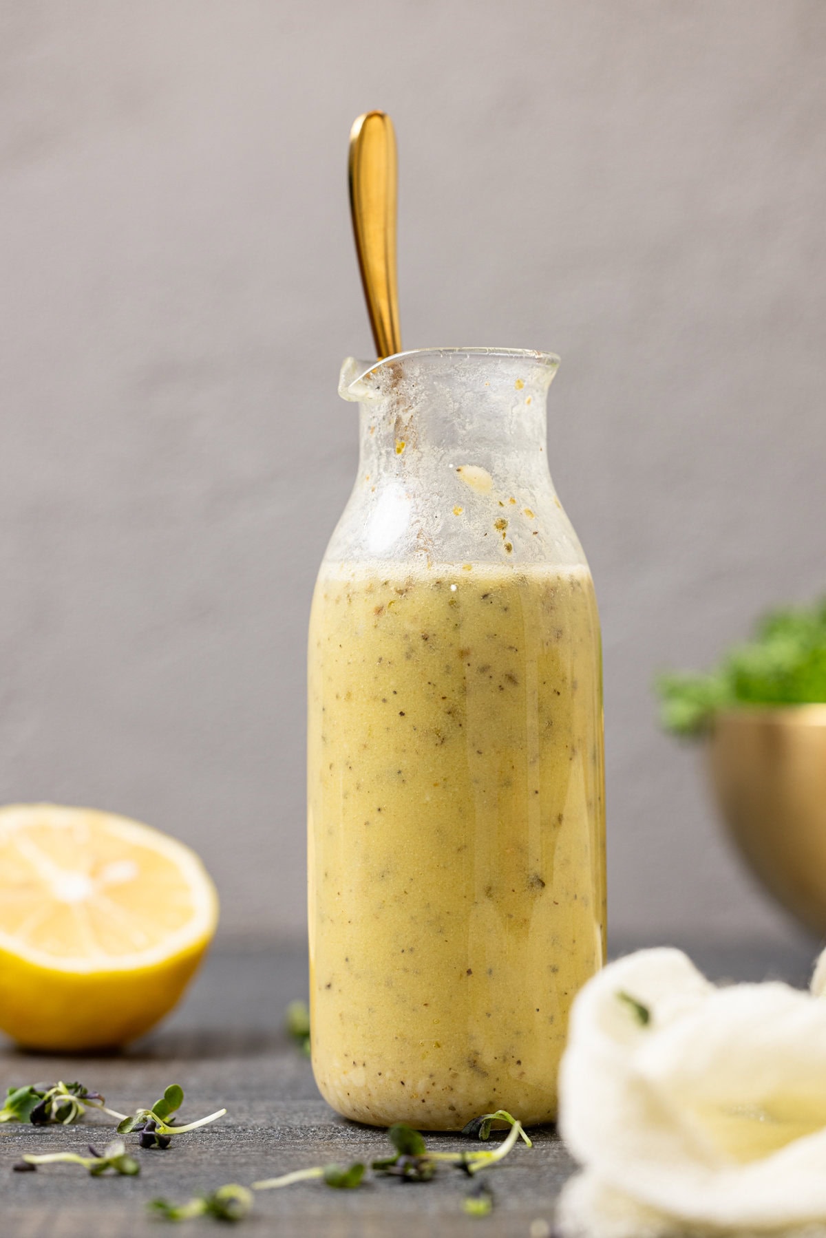 Up close shot of dressing in a jar with a spoon and lemon.