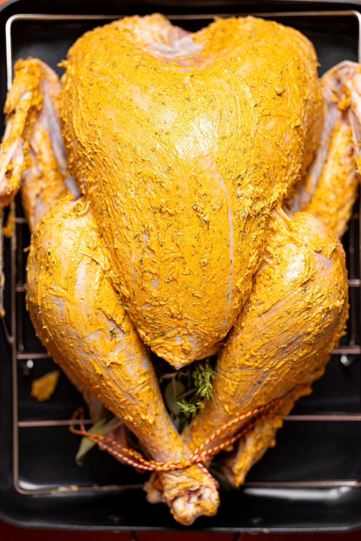 Turkey on a roasting pan smeared with herb butter.