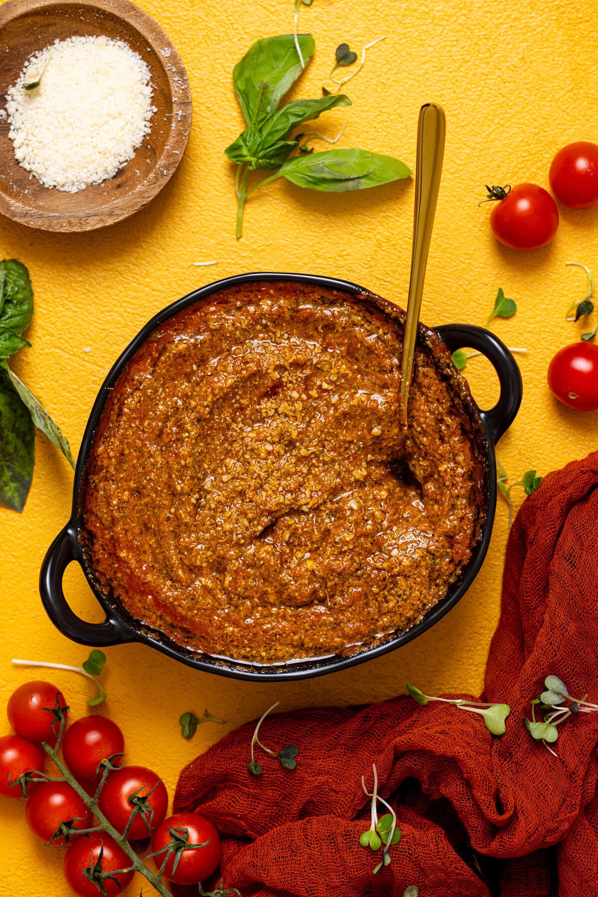 Tomato pesto in a black bowl on a yellow table.